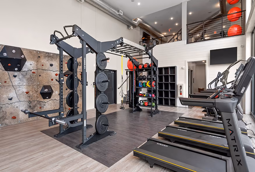 Multi-level gym with a squat rack, cable machine, and sport flooring