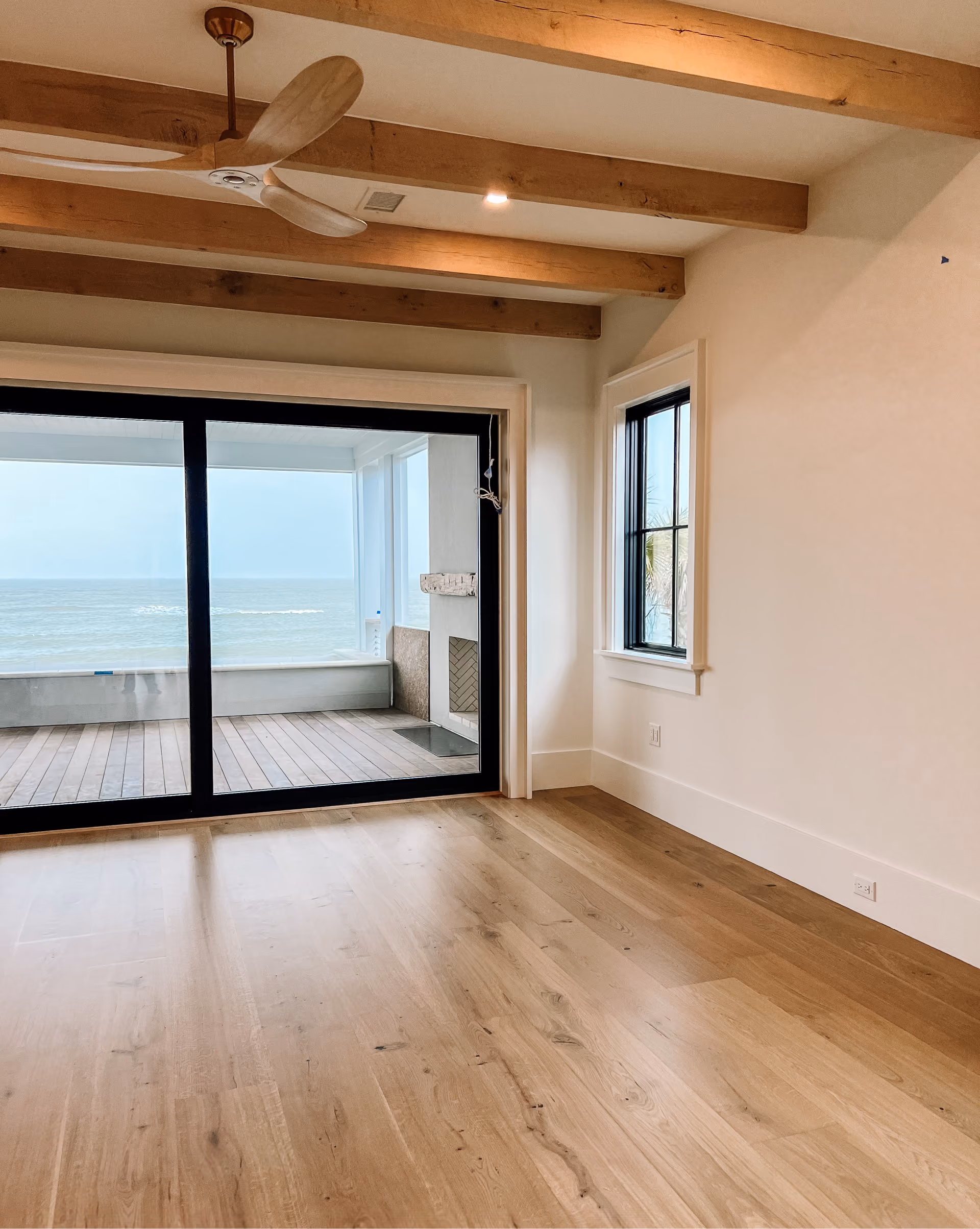 Room with sliding glass doors, an ocean view, and light hardwood flooring