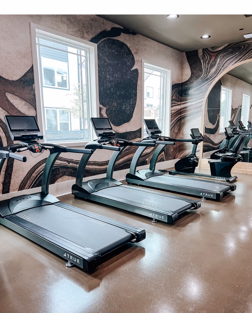 Gym with treadmills and a mural accent wall on sport flooring