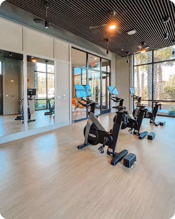 Gym room with spin bikes and floor-to-ceiling mirrors on wood-look sport flooring