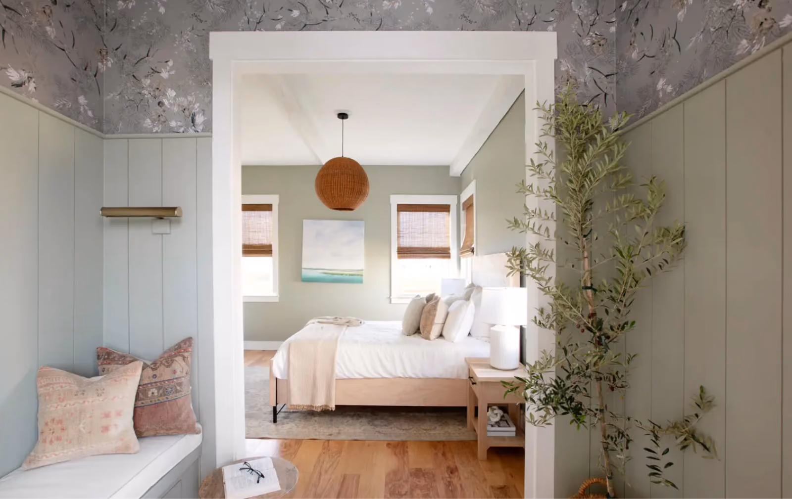 Bedroom with a green accent wall and light wood-look flooring