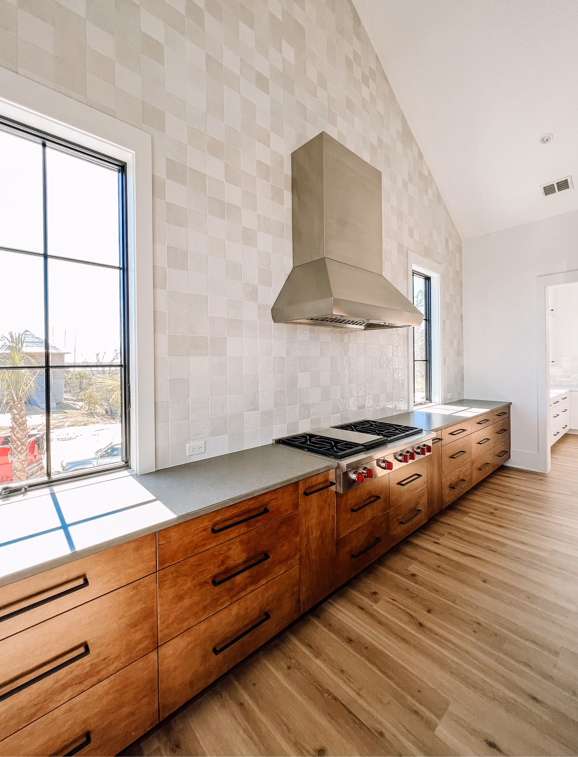 Kitchen with a wood range hood, dark wood island, and hardwood flooring