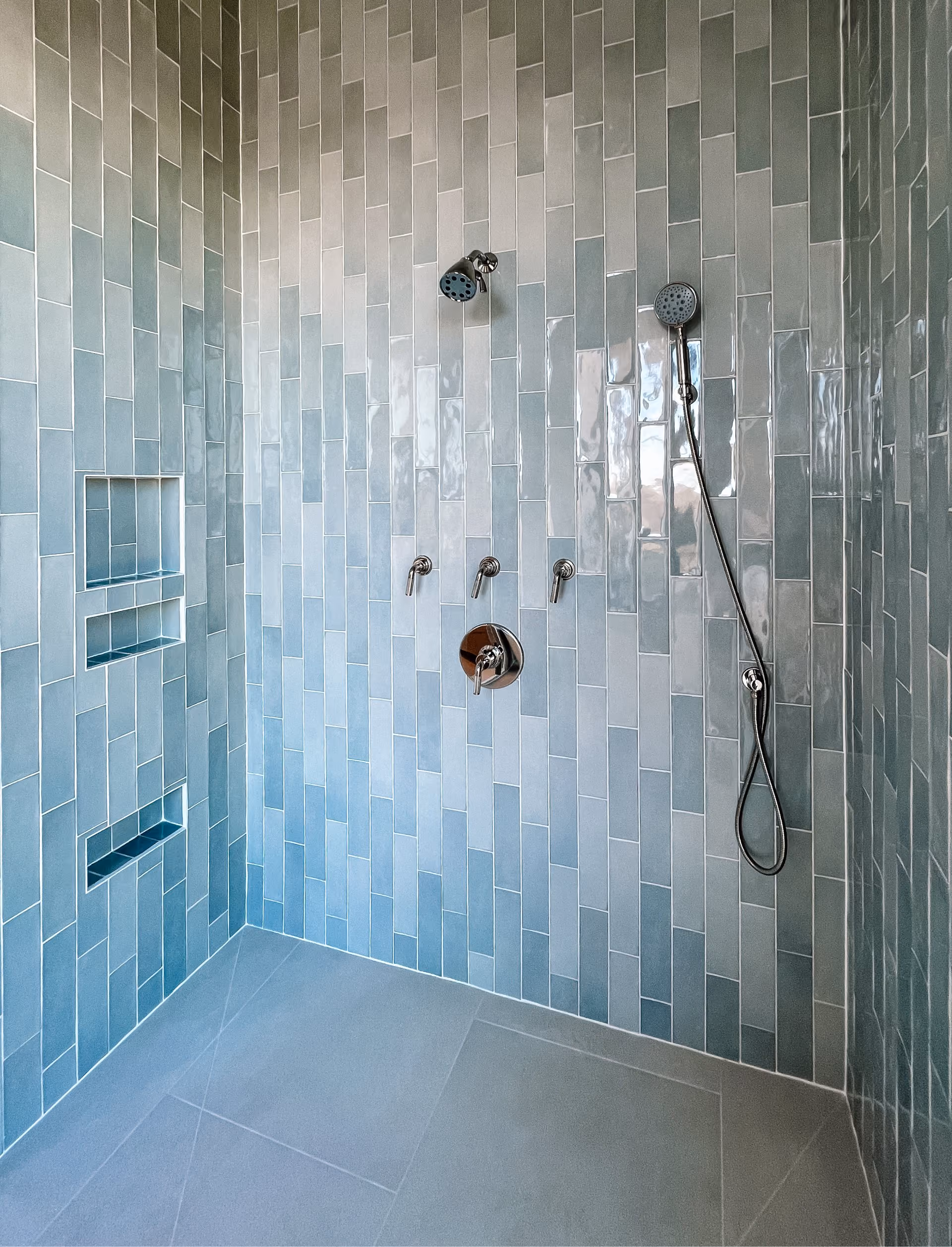 Close-up of a shower with teal glazed tile walls
