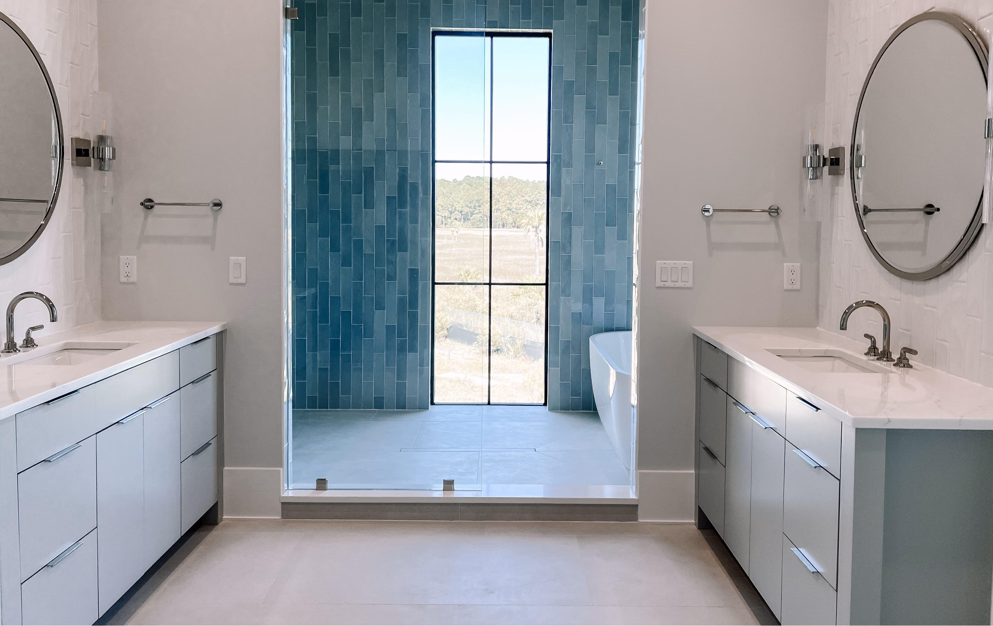 Bathroom with teal tile walls, a glass shower, and a double vanity