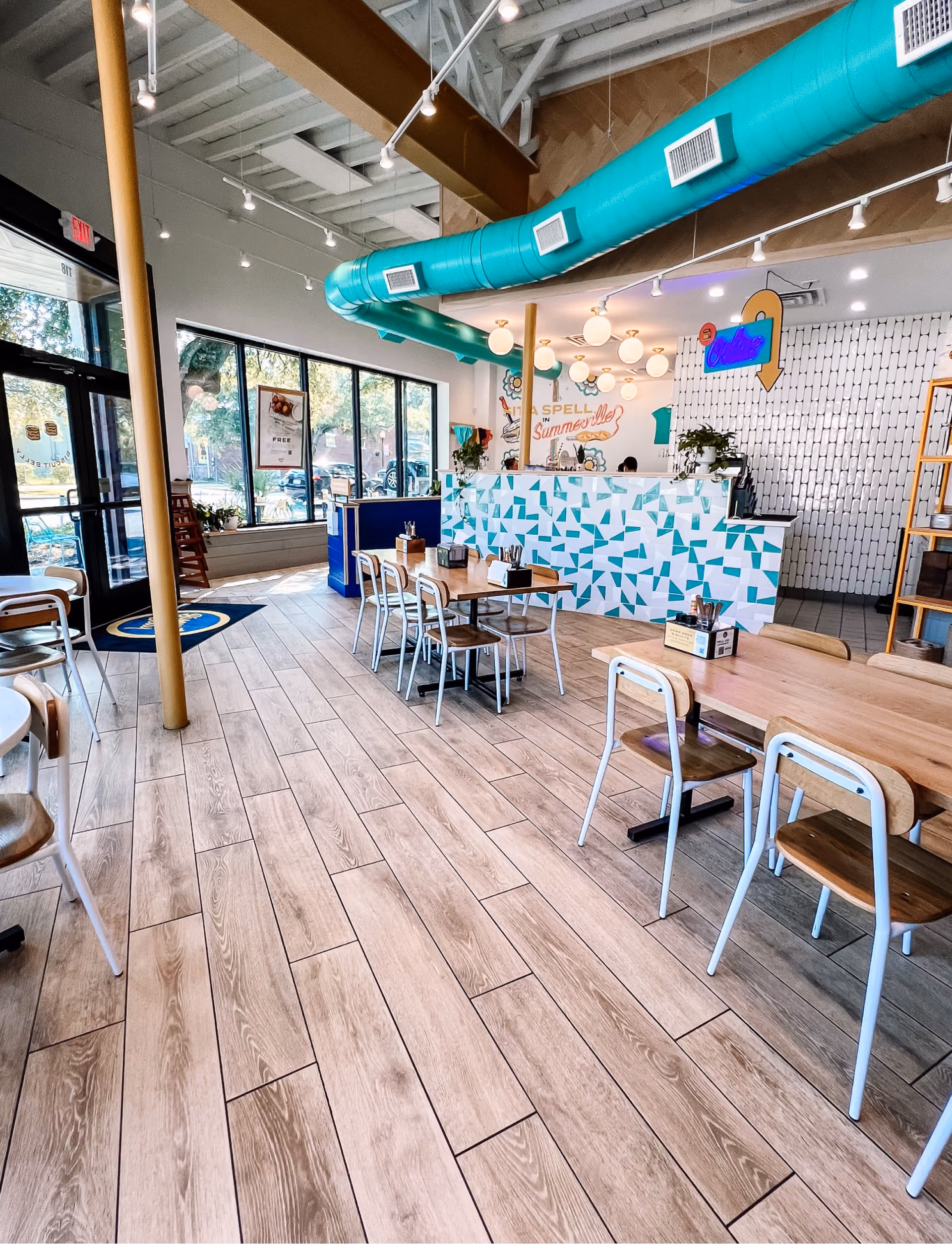 Restaurant dining area with wood tables and terrazzo-look tile flooring near windows