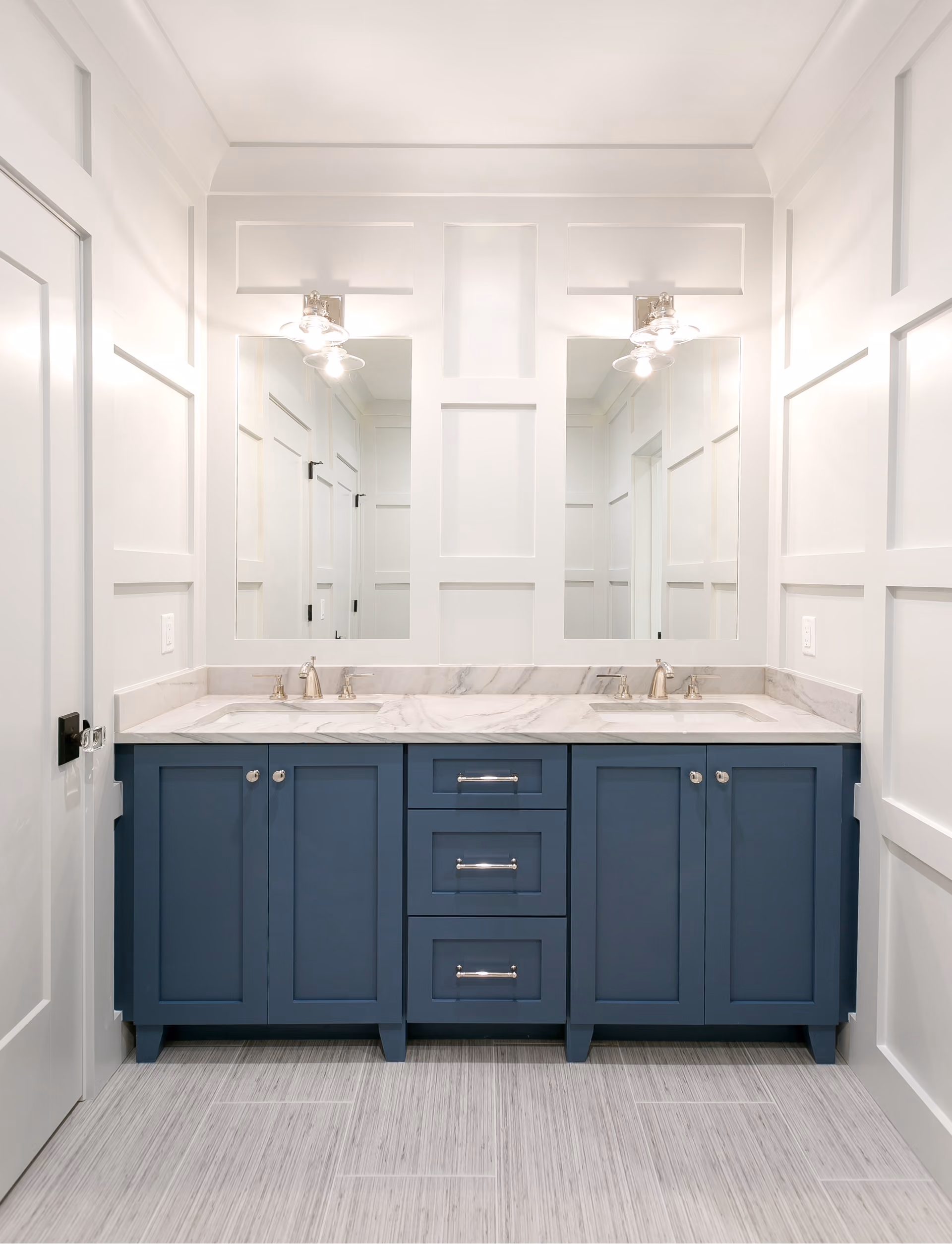 Bathroom double vanity with navy cabinetry and a marble countertop
