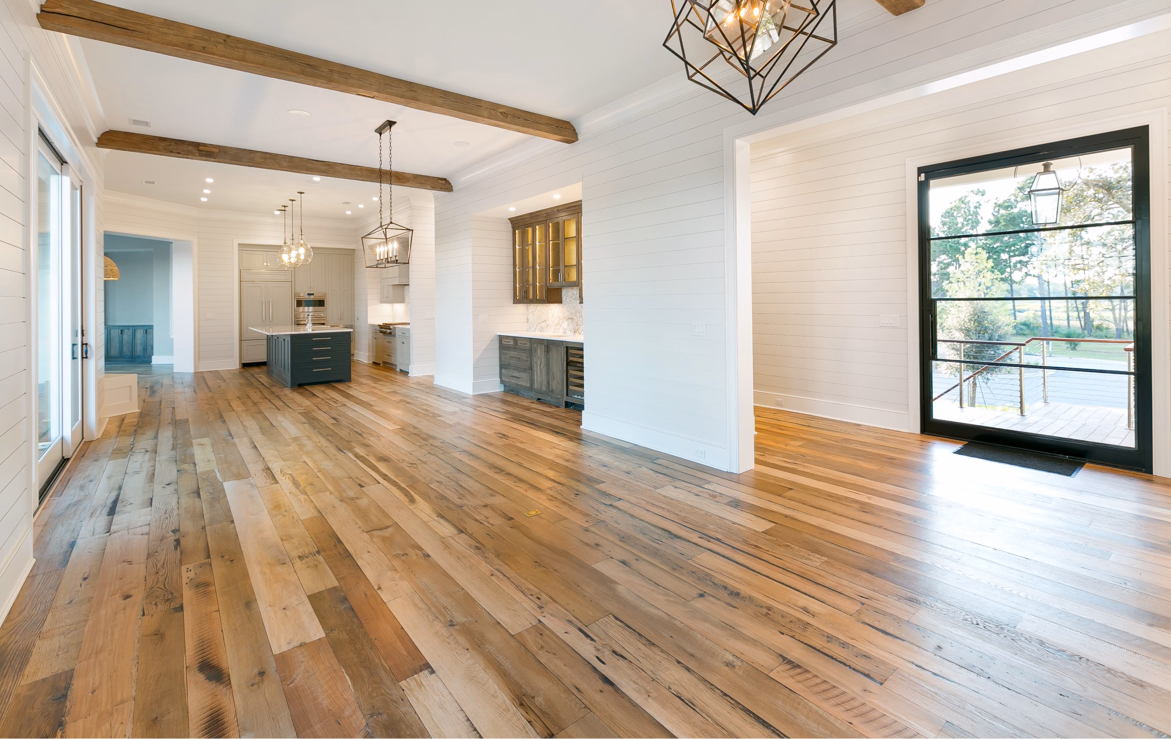 Living and dining room with wide-plank hardwood flooring and a beamed ceiling