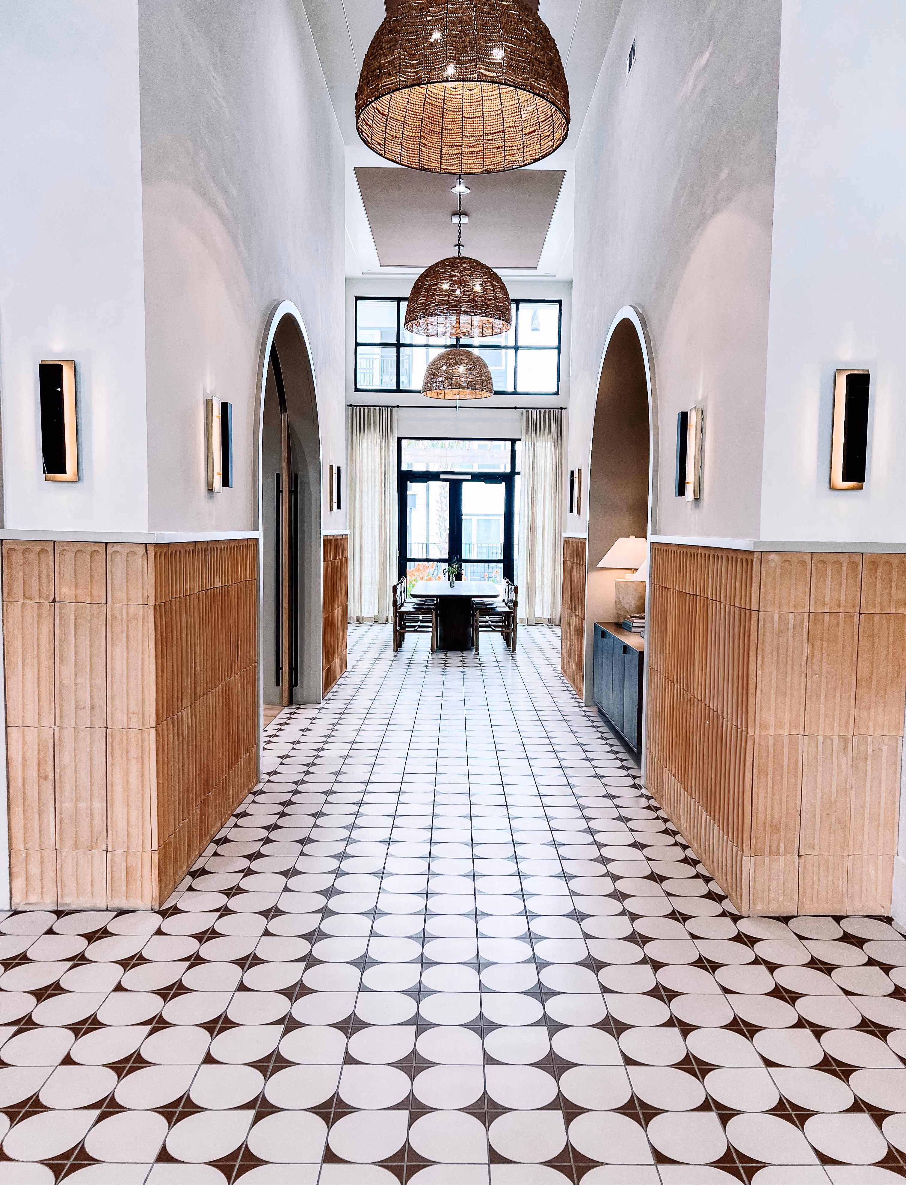 Arched hallway with wood paneling and patterned tile flooring