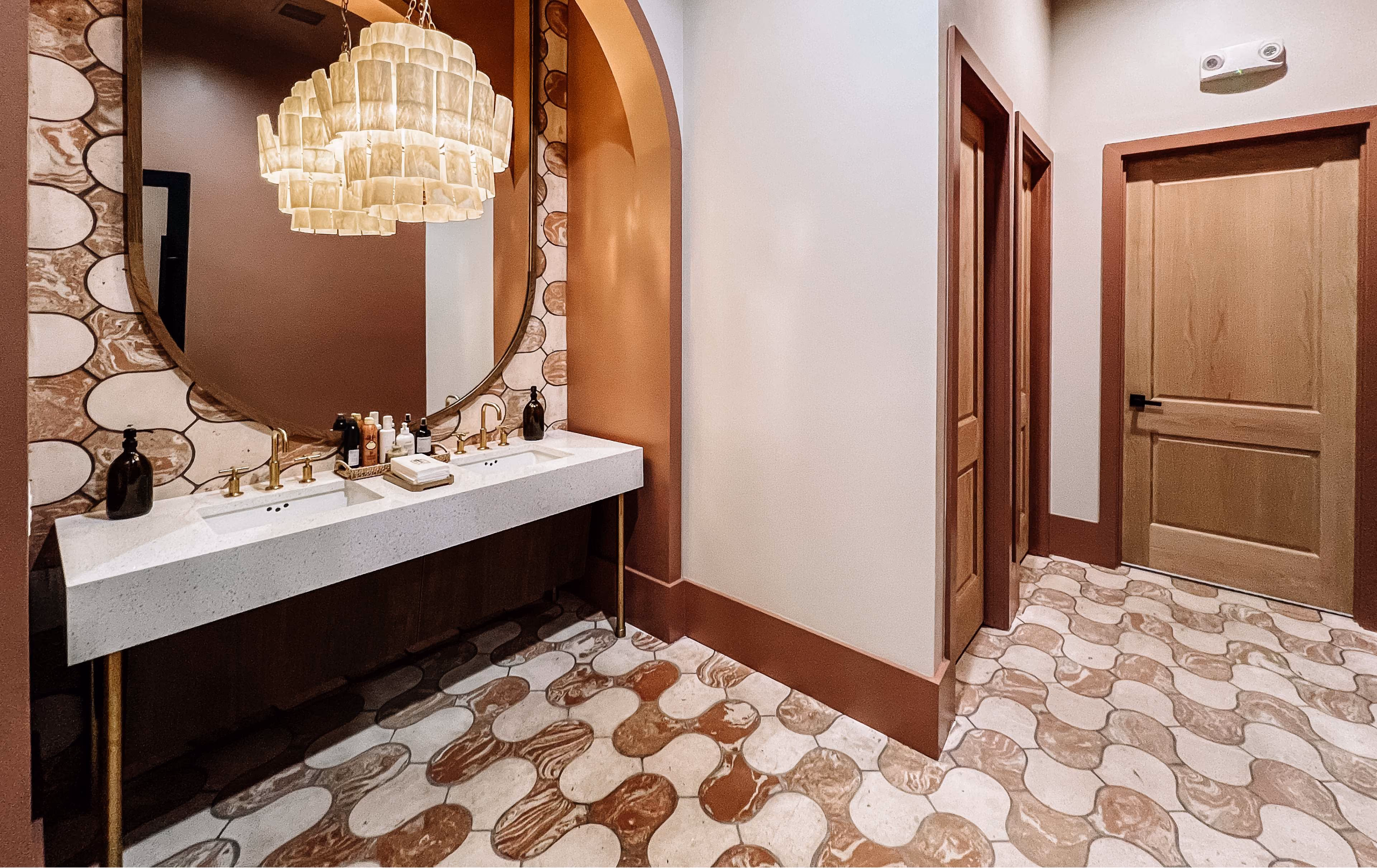Bathroom vanity with an arched mirror and patterned tile flooring