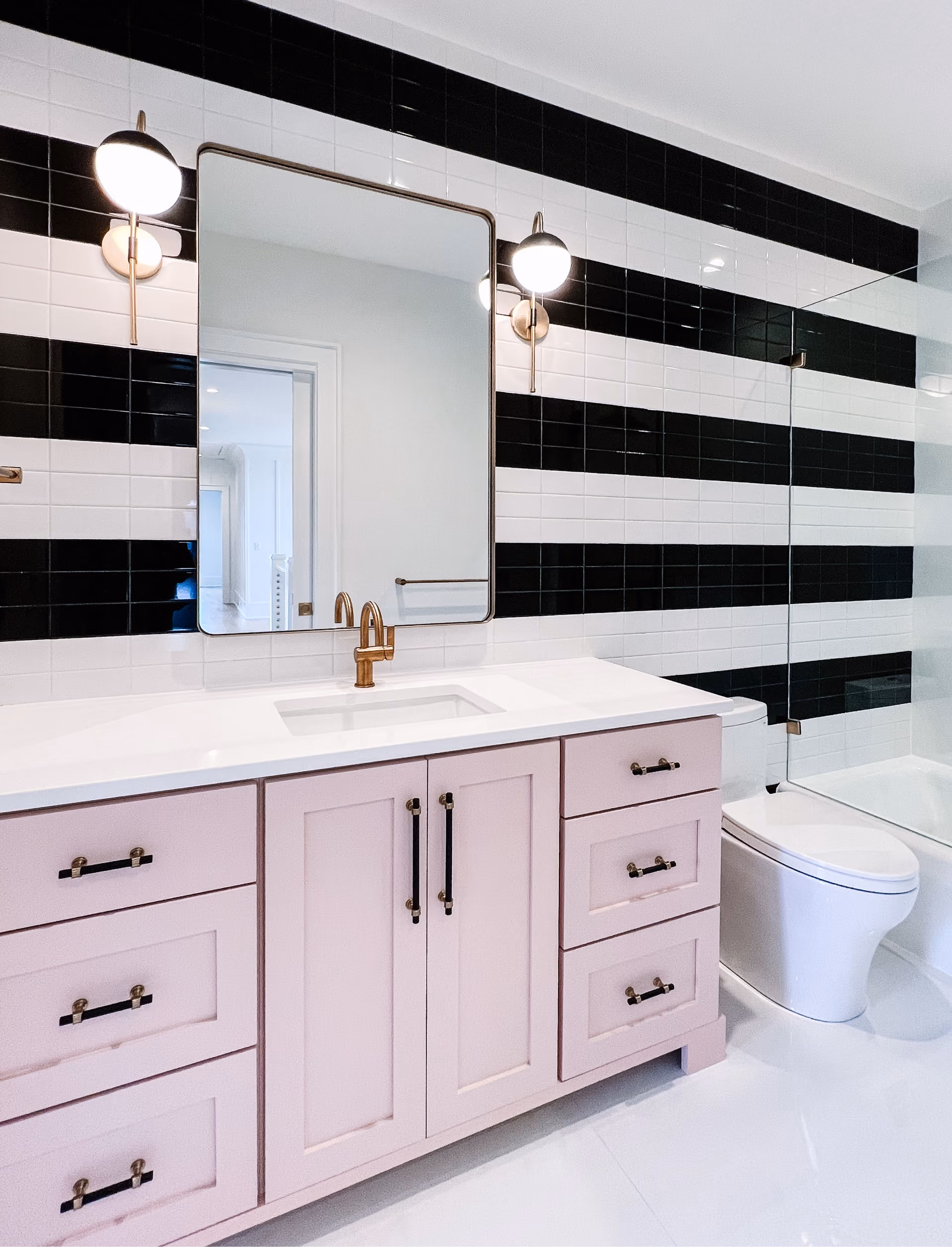 Bathroom with black-and-white striped tile walls and pink vanity cabinetry