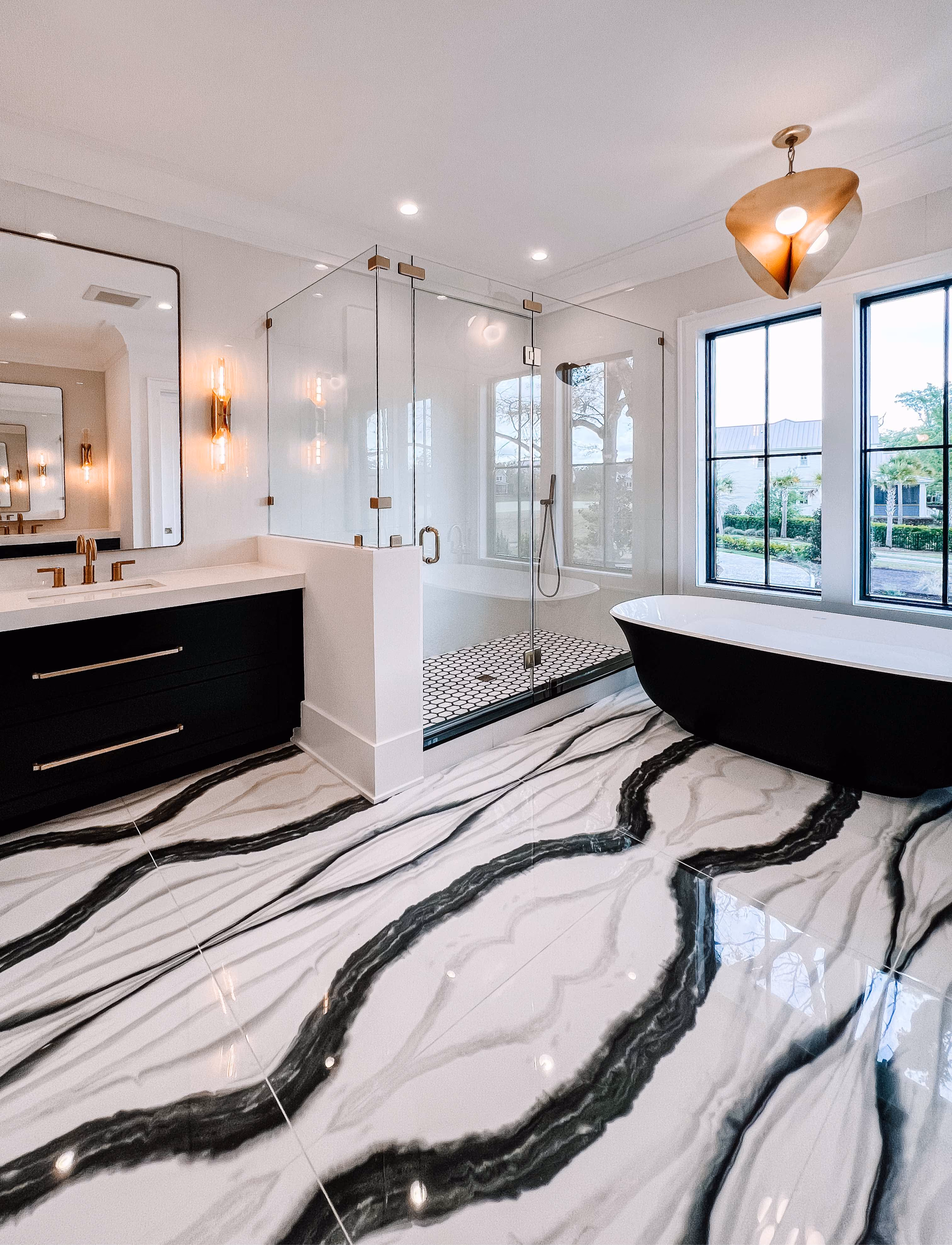 Bathroom with a black freestanding tub on dramatic black-and-white marble-look tile flooring