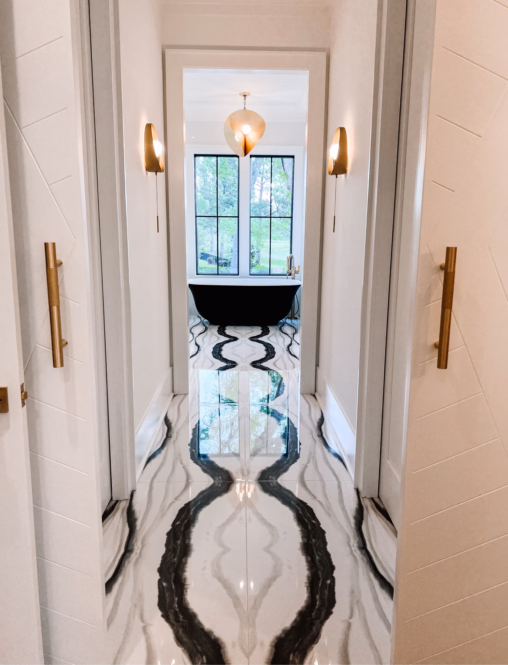 Hallway with black-and-white marble tile flooring and brass hardware