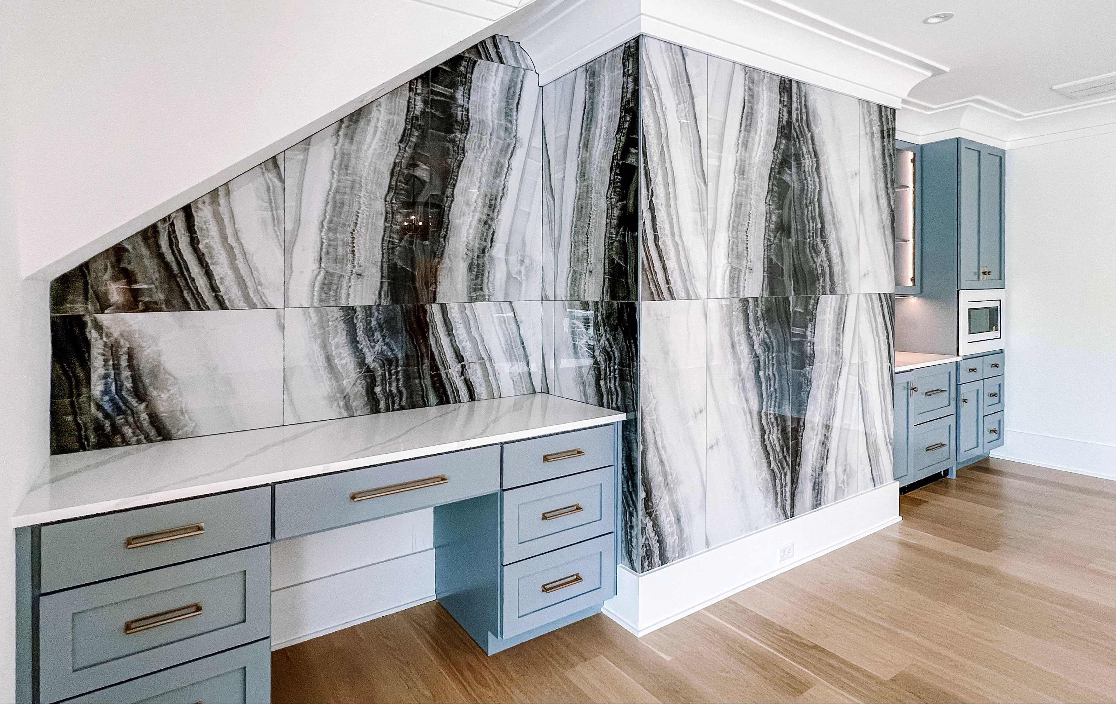 Built-in desk nook with dramatic marble-look wall tile and wood-look flooring