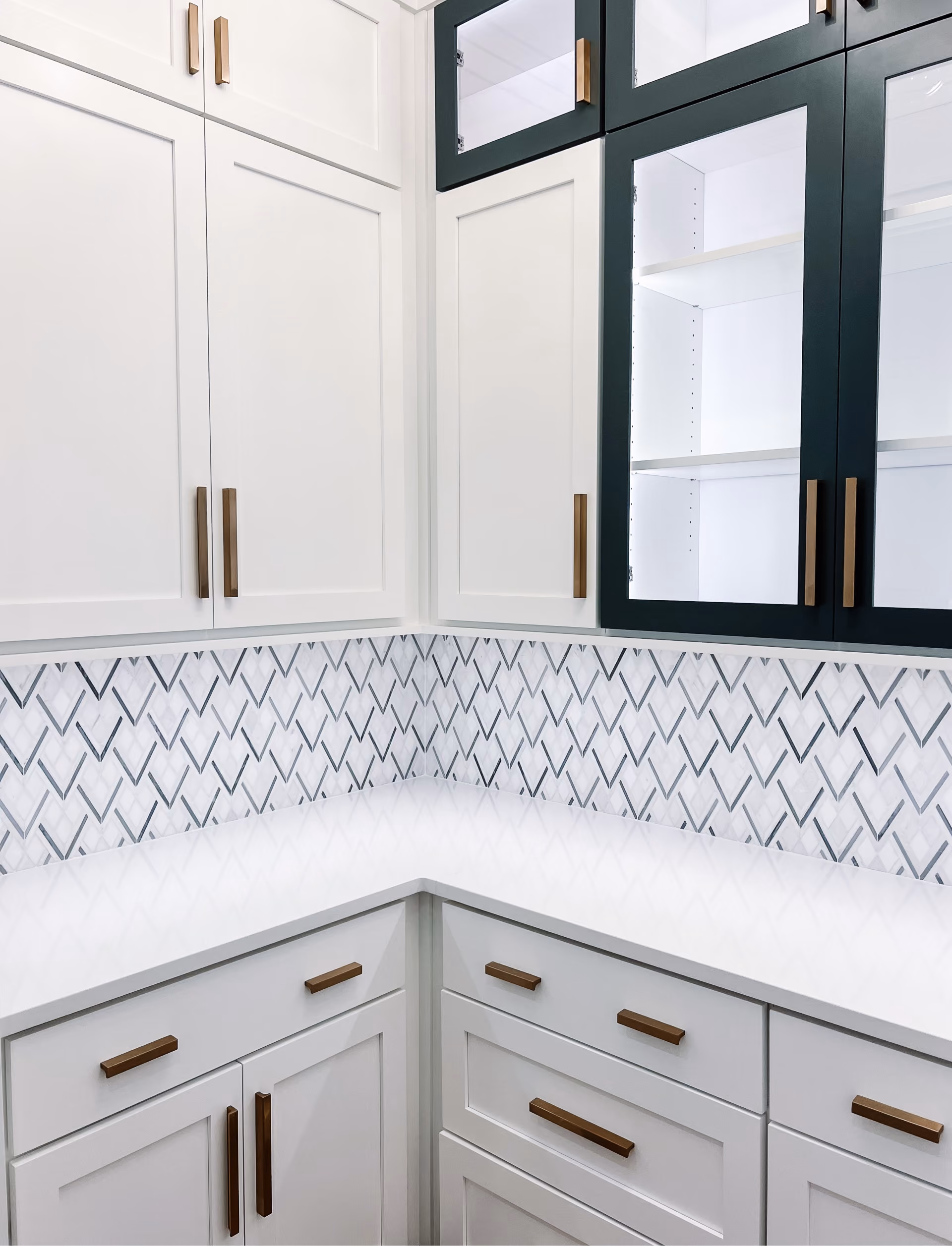 Bathroom corner with white chevron-pattern tile walls and a marble countertop