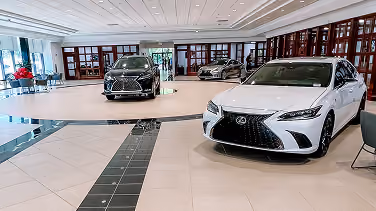 Car dealership showroom with luxury vehicles on black-and-white tile flooring
