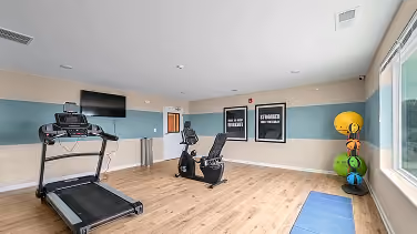 Senior living fitness room with exercise equipment on wood-look flooring