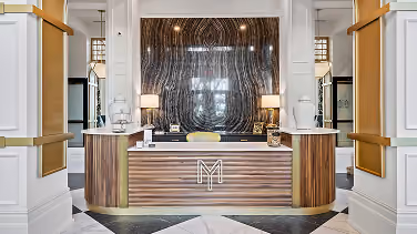 Multi-family lobby reception desk with a marble-look wall and patterned tile flooring