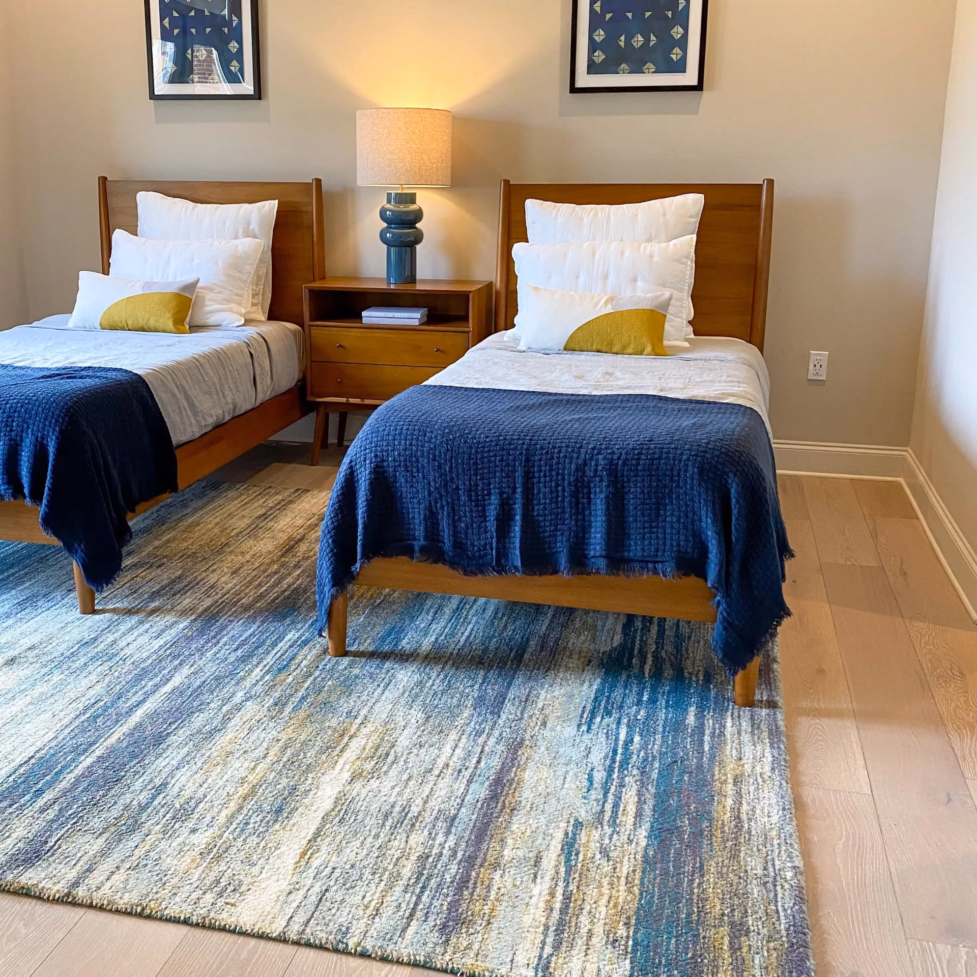 Student apartment bedroom with navy bedding and light gray carpet flooring