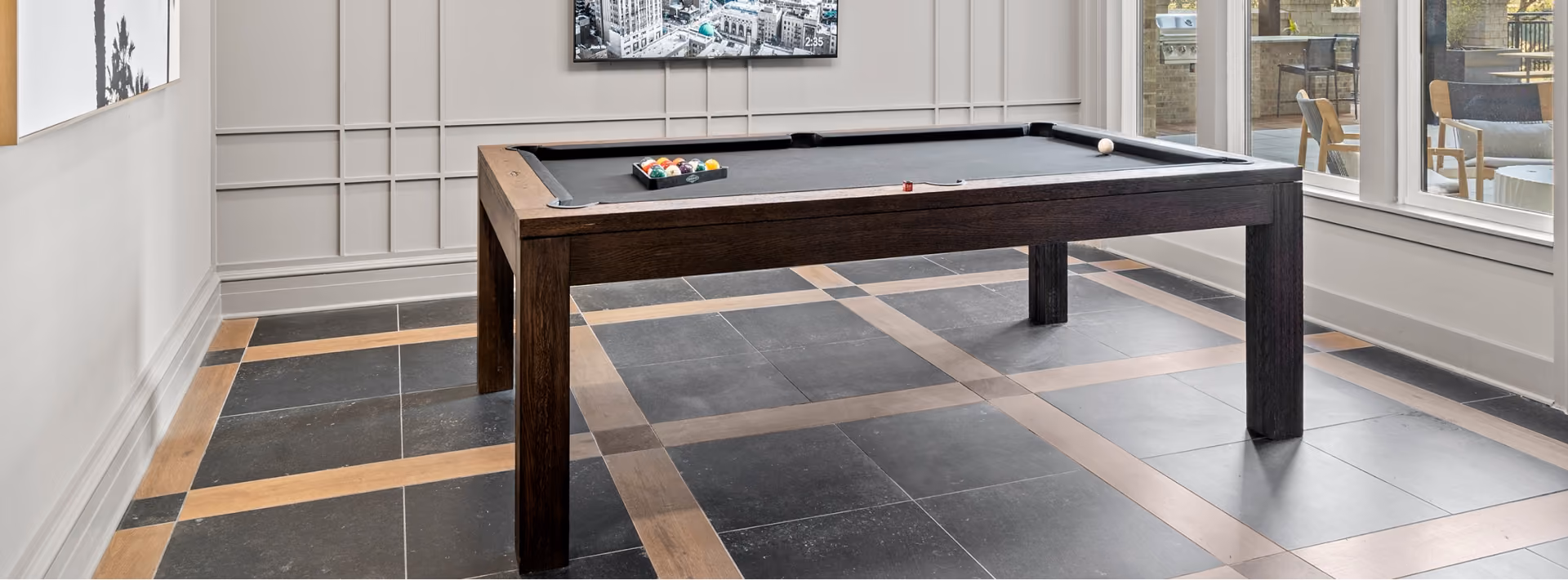 Hotel billiards room with dark checkerboard-pattern floor tile and a pool table