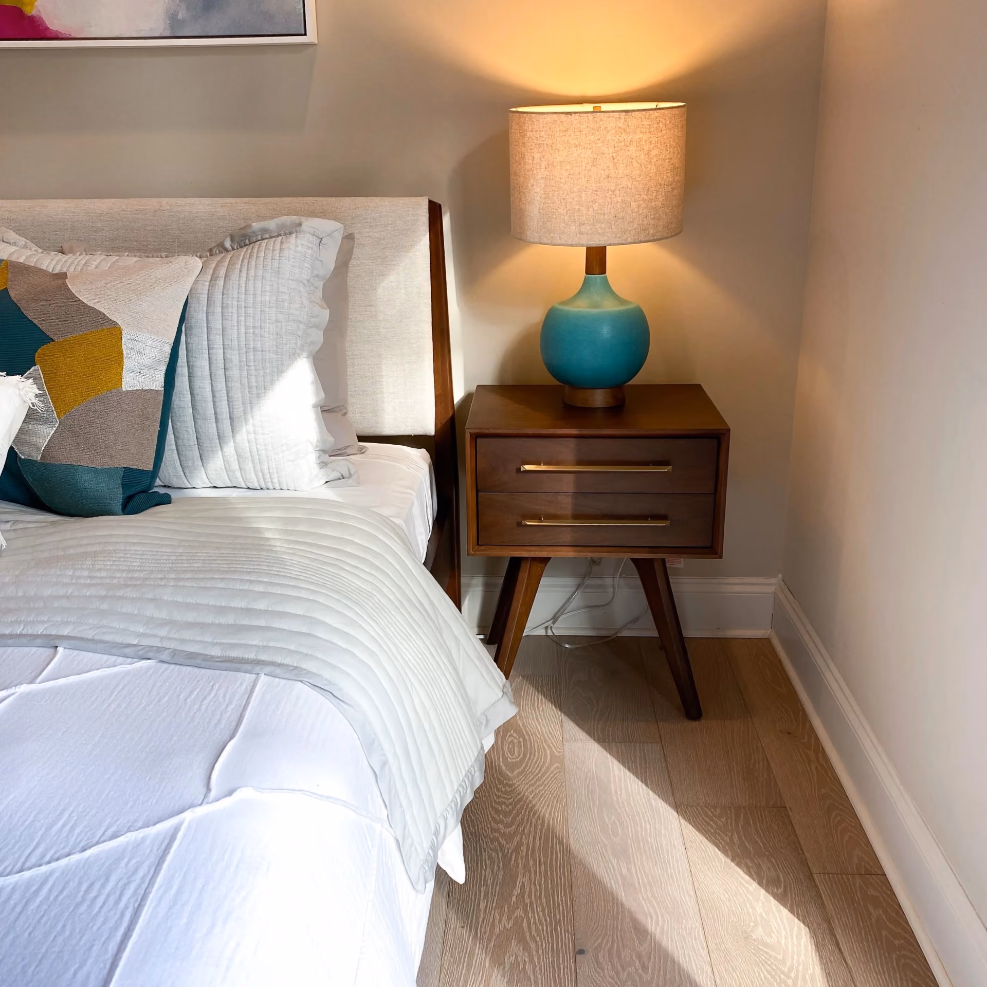 Student apartment bedroom with a nightstand and light gray carpet flooring