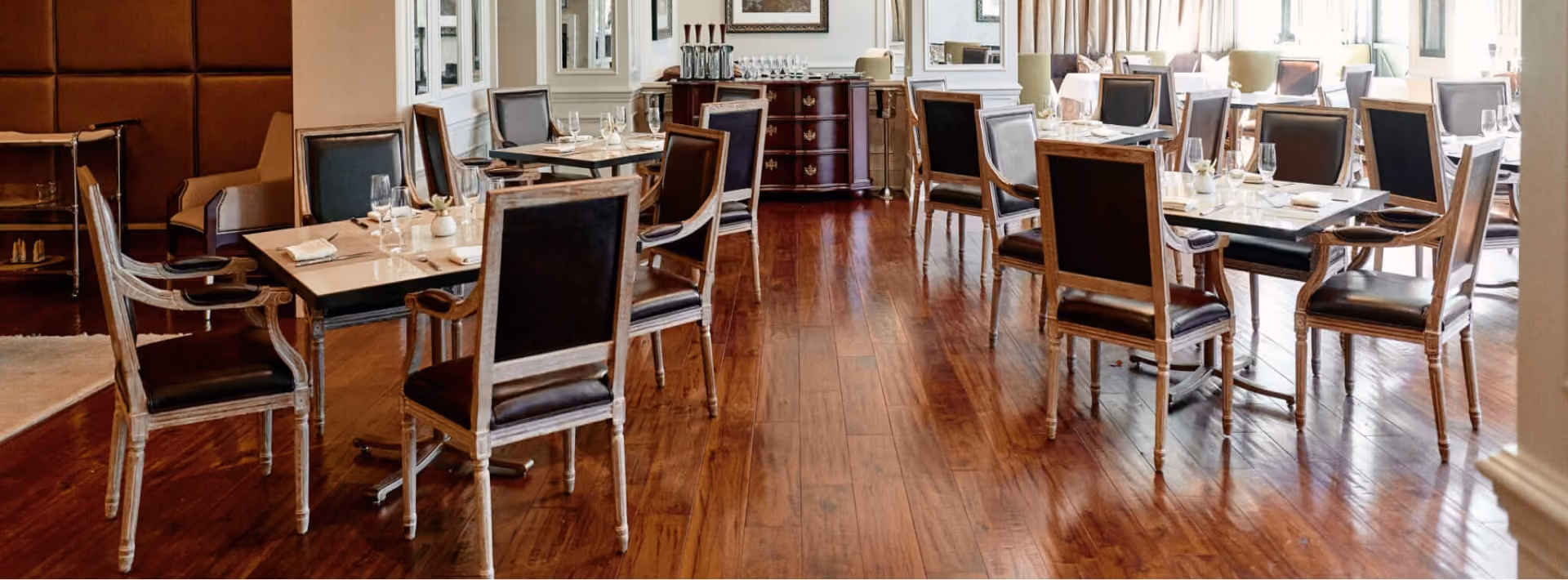Hotel dining area with rich wood flooring and dining chairs