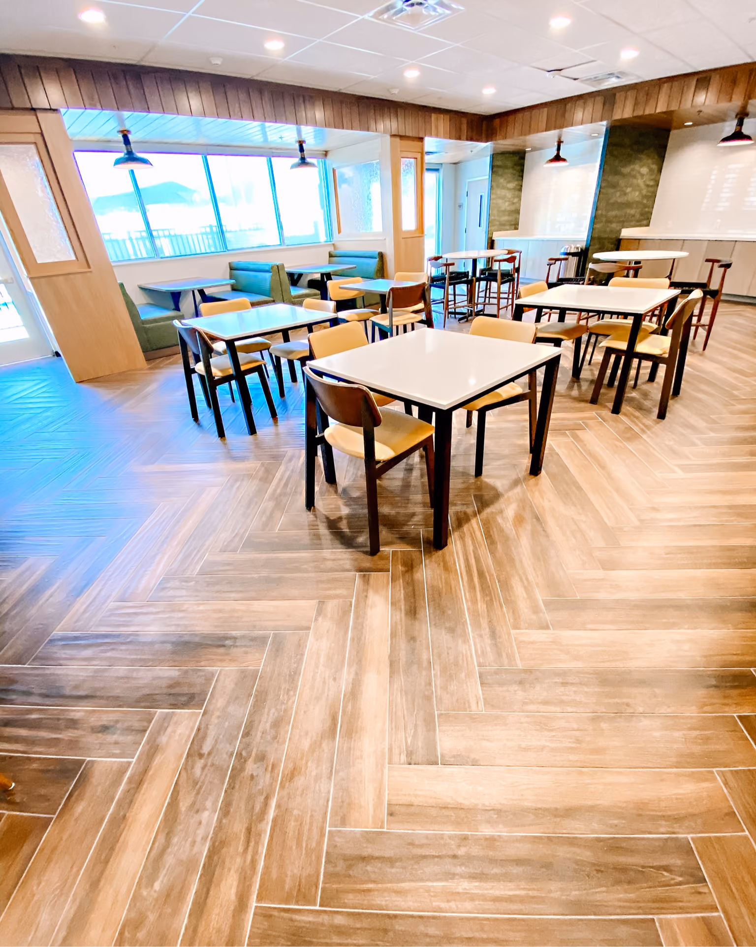 Hotel restaurant with round tables, dark chairs, and wood-look flooring