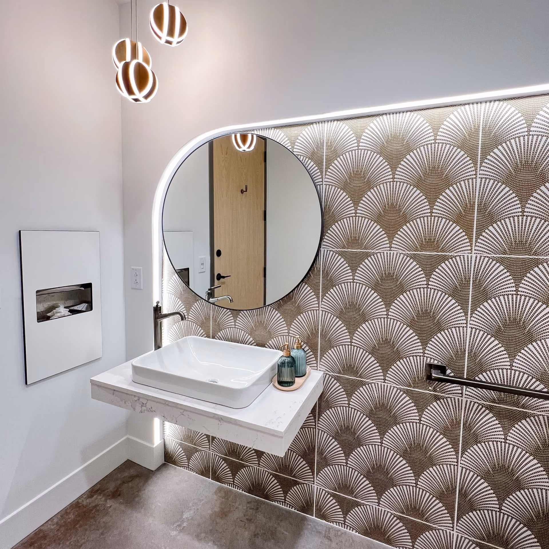 Healthcare facility restroom with a patterned mosaic accent wall and light flooring