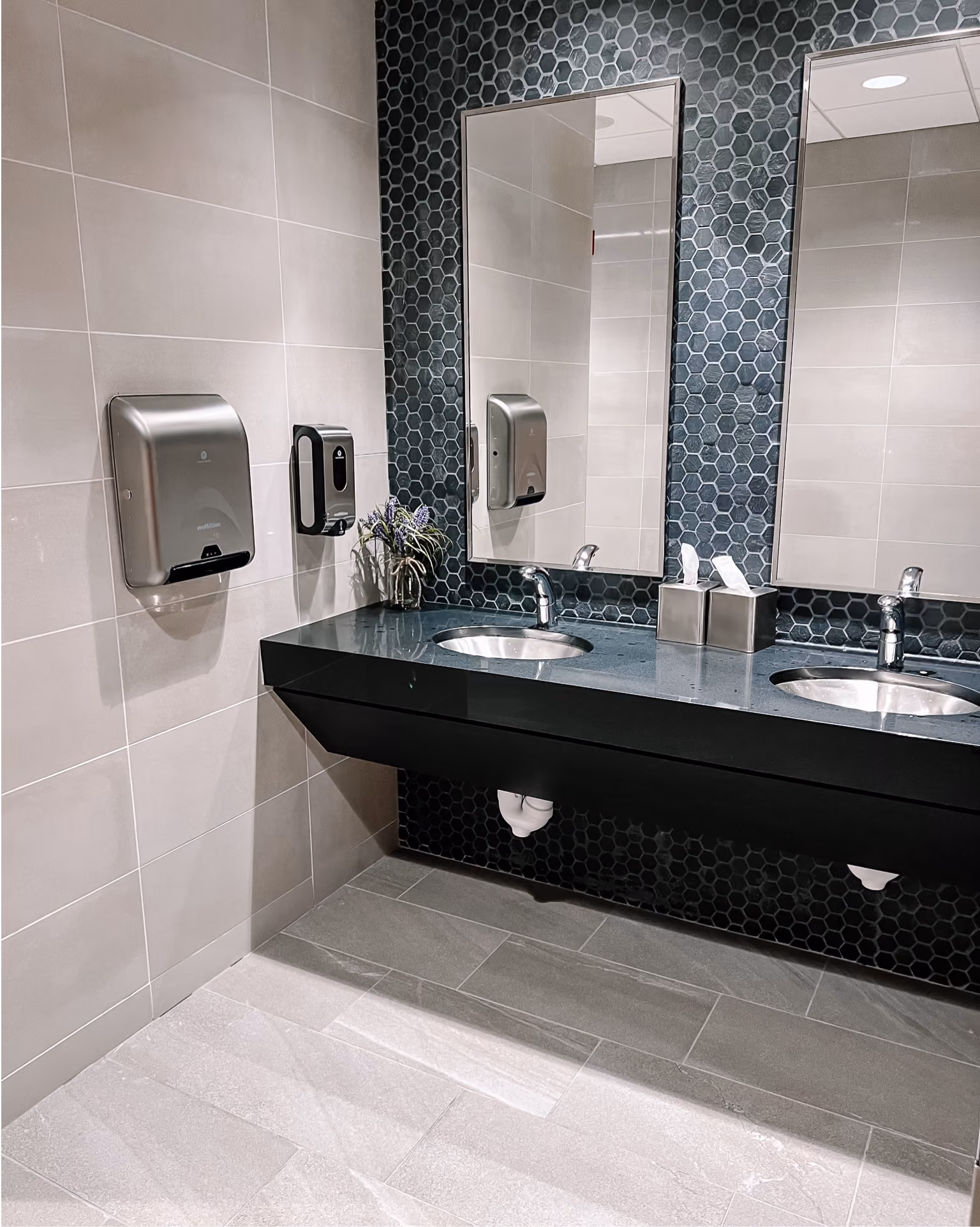 Dealership restroom with dark mosaic tile flooring and a vanity