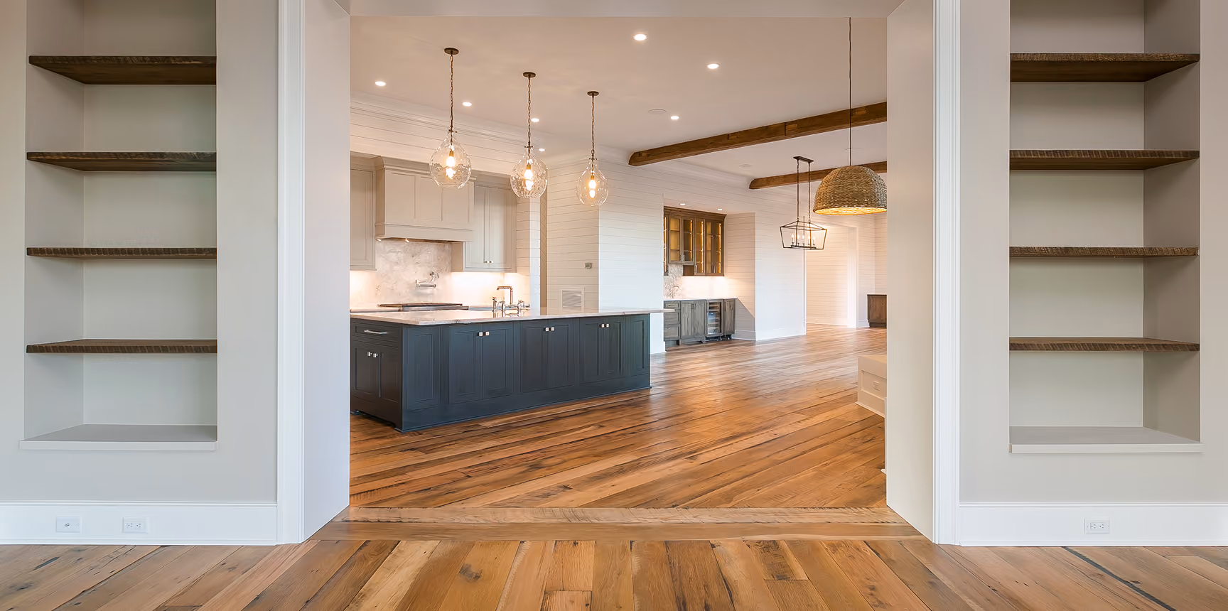 Newly constructed kitchen and living area with hardwood flooring and navy cabinetry