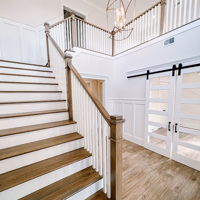 Staircase in a new construction home with wood flooring and white risers