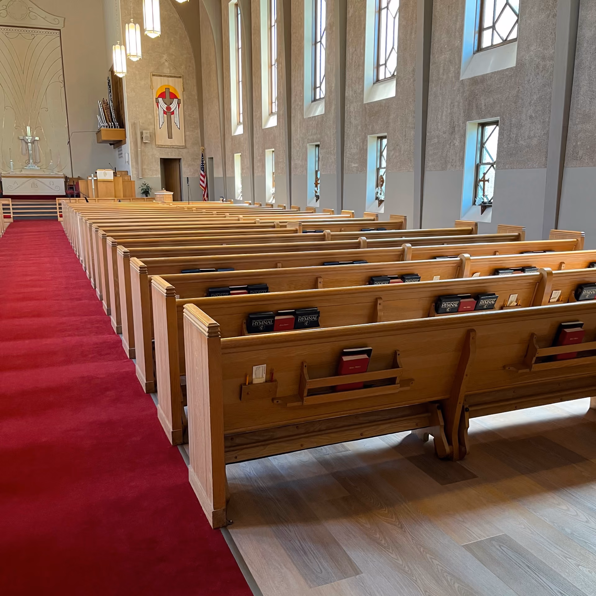 Church sanctuary with rows of wood pews and a red aisle carpet runner