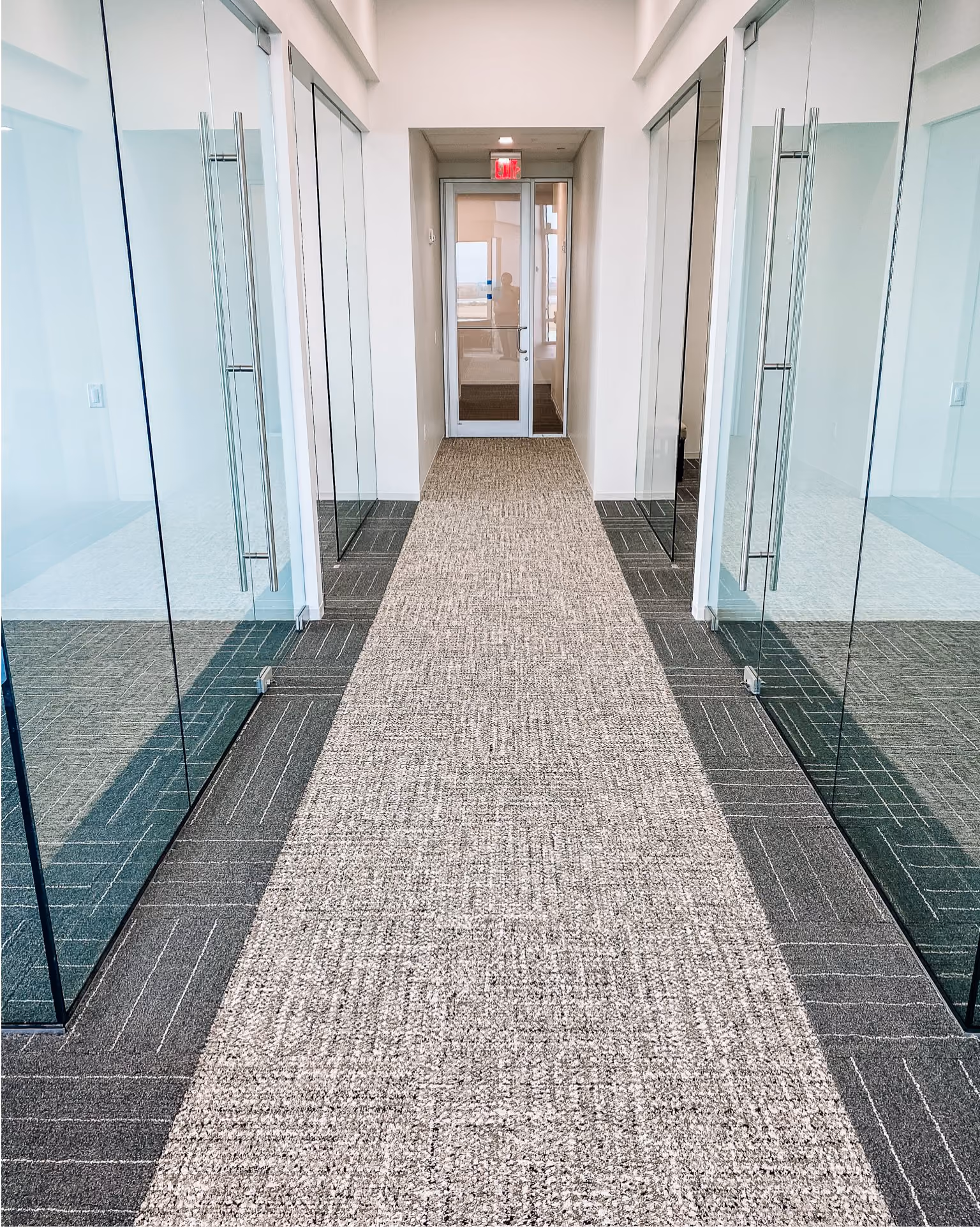 Office corridor with speckled terrazzo-look flooring leading to glass doors