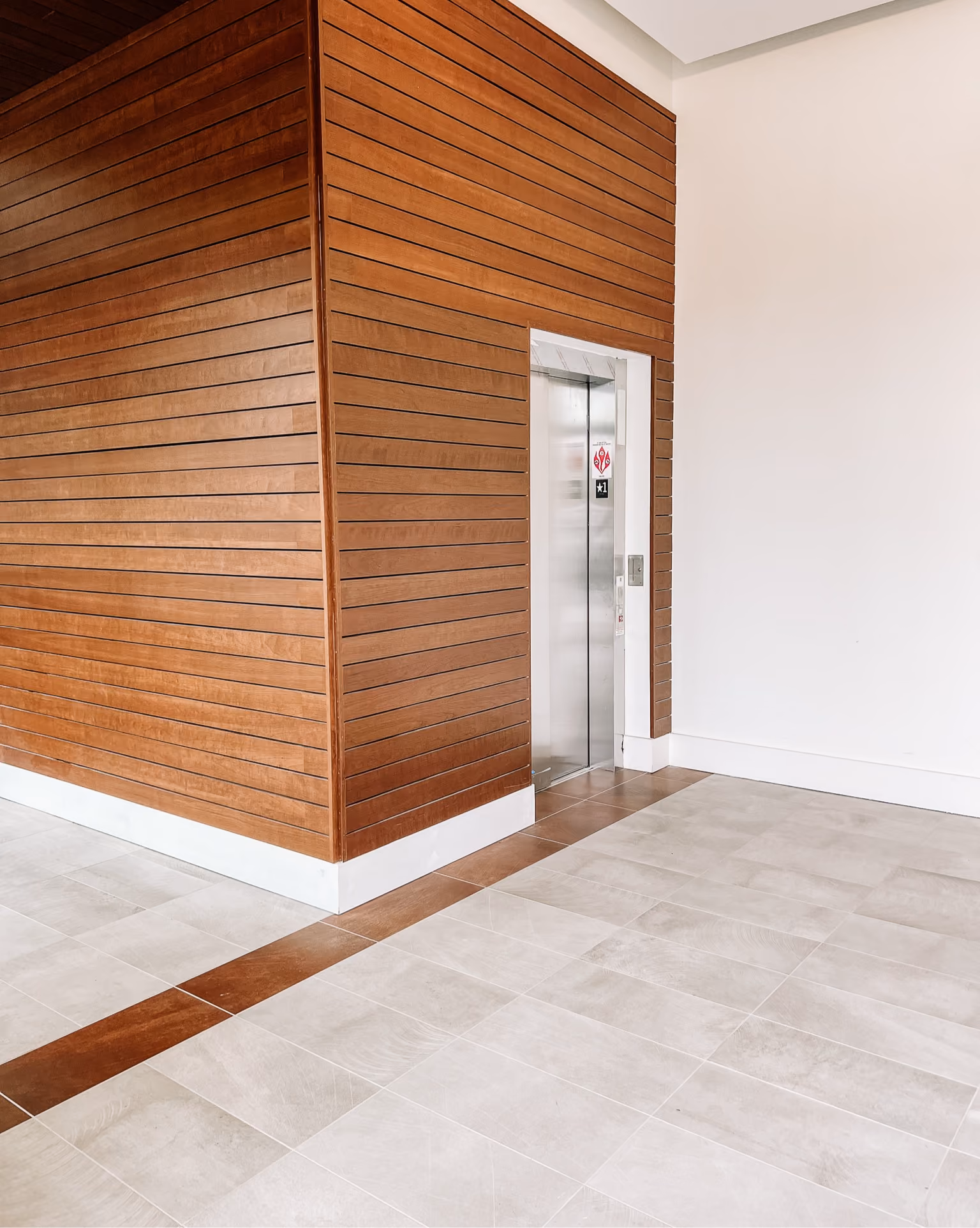 Office hallway with a decorative rust-orange perforated wall panel and light wood-look flooring