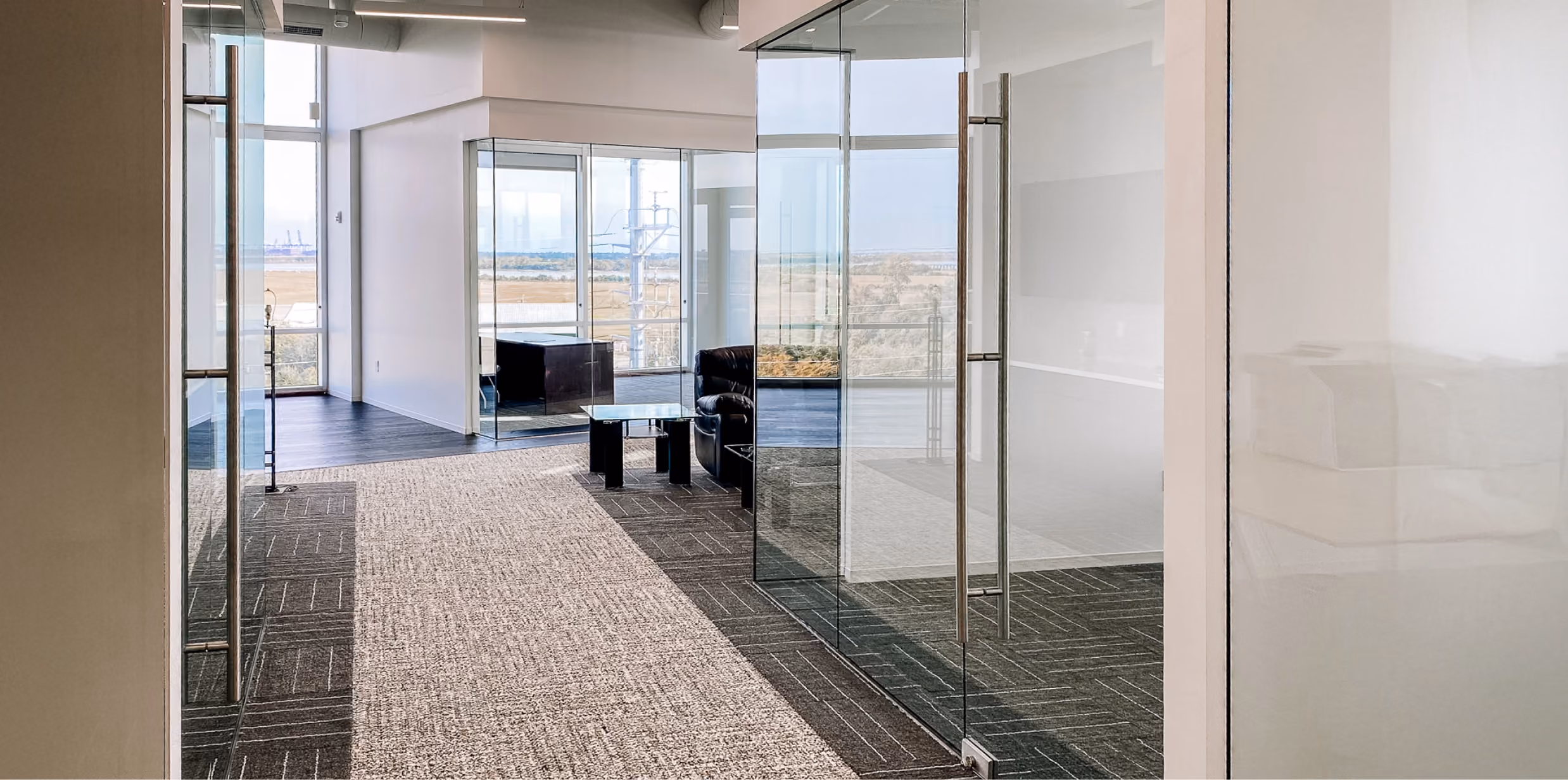 Modern office reception area with glass partition walls and dark speckled terrazzo-look flooring
