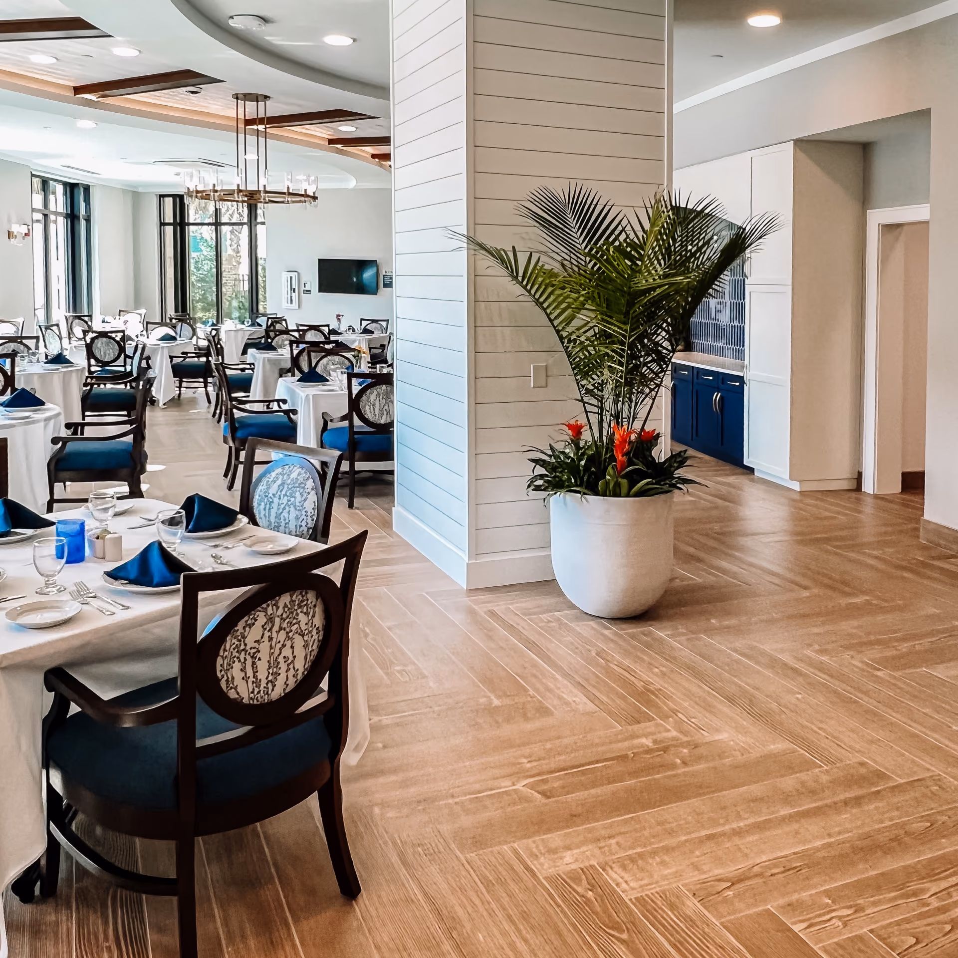 Senior living common room with dining tables and light wood-look flooring