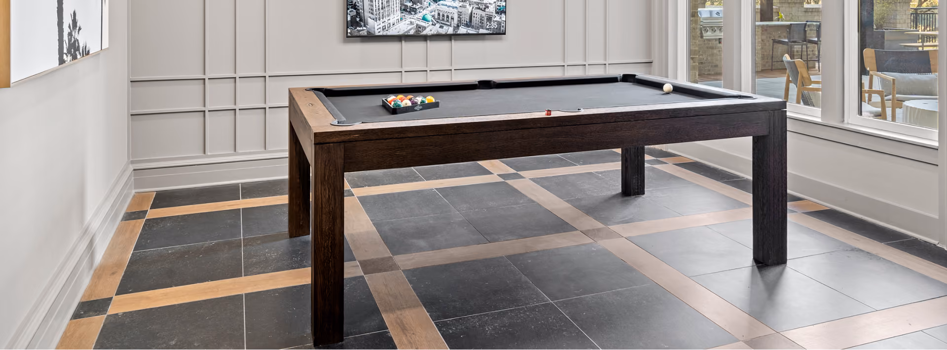 Hotel billiards area with a pool table on dark checkerboard-pattern floor tile