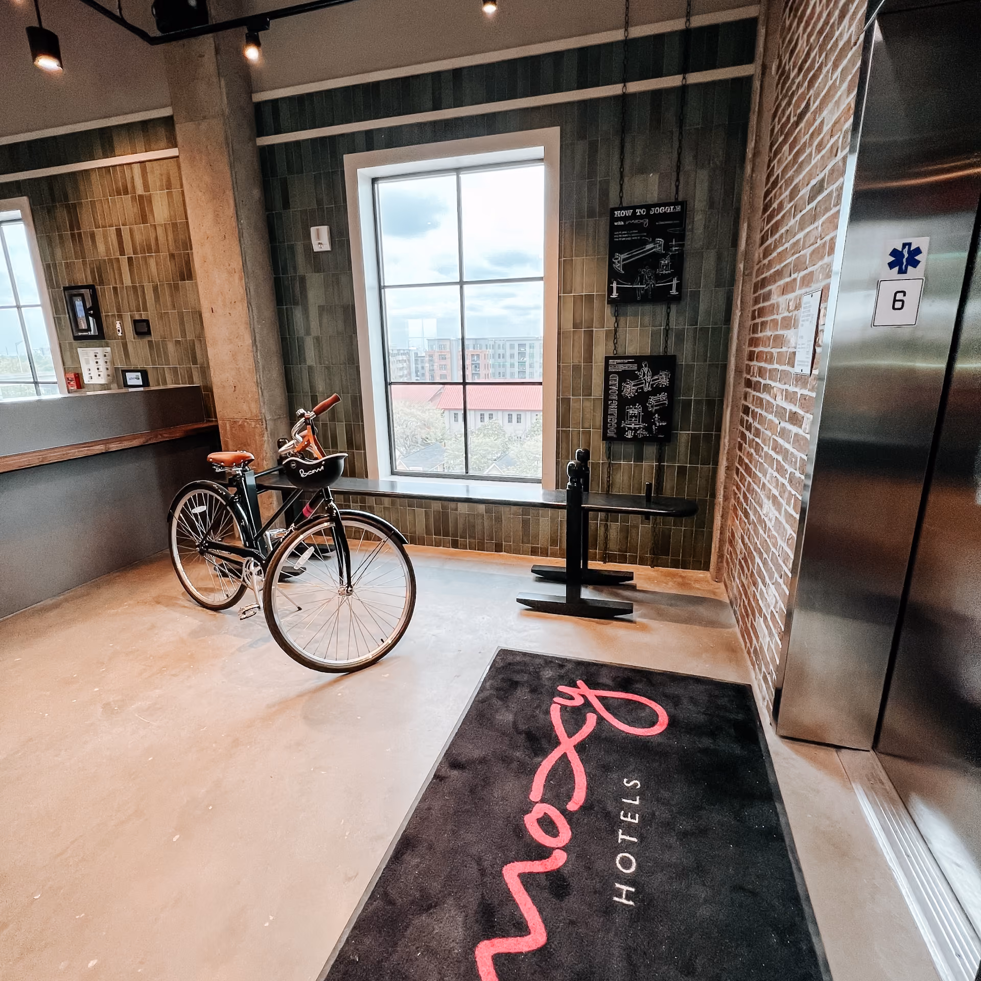 Hotel guest room with an exposed brick wall, a bicycle, and light wood-look flooring