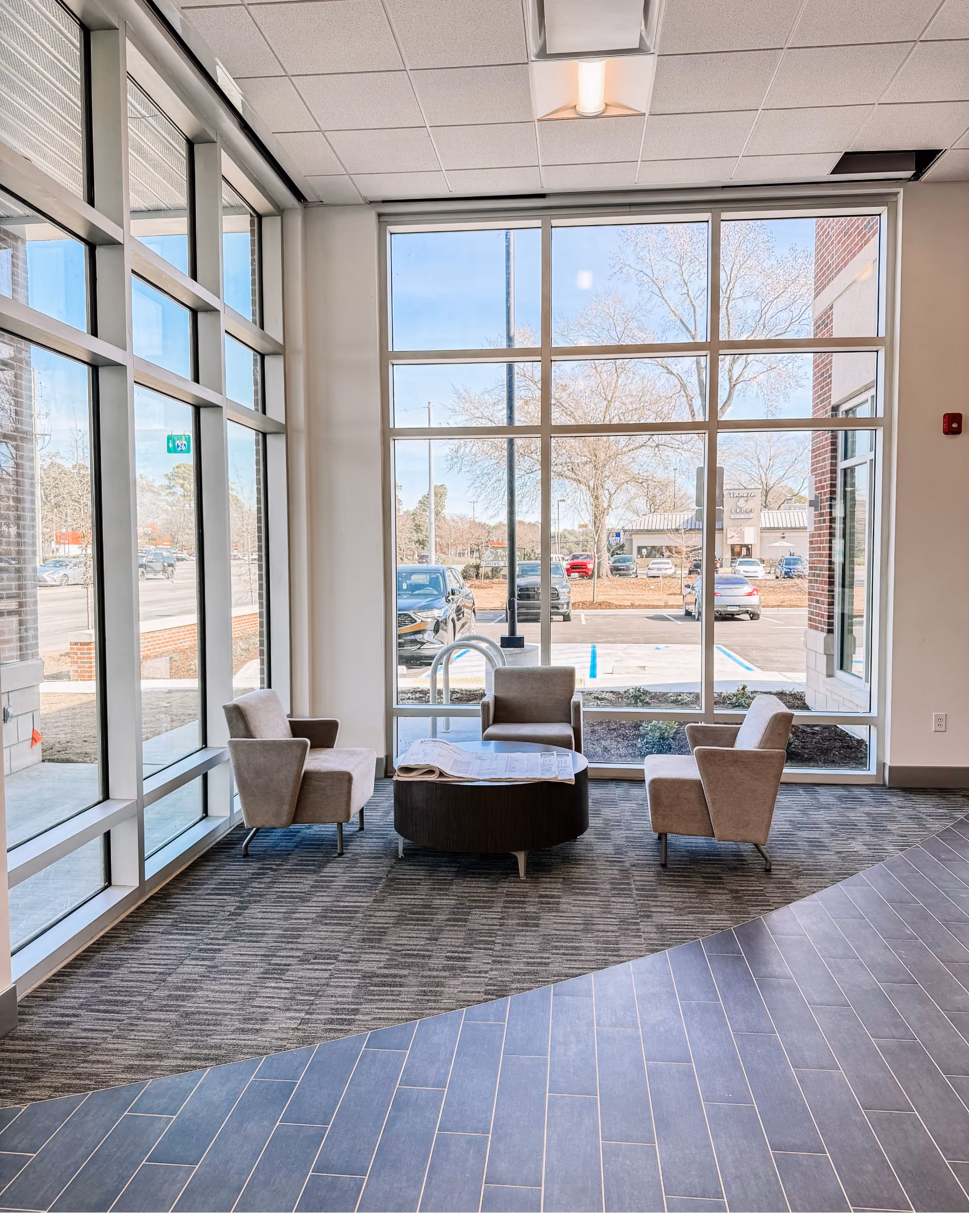 Bank lounge seating area with large windows and patterned carpet flooring