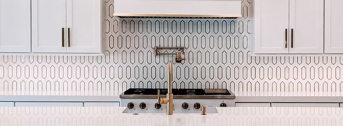 Residential kitchen backsplash detail with a cooktop and patterned tile