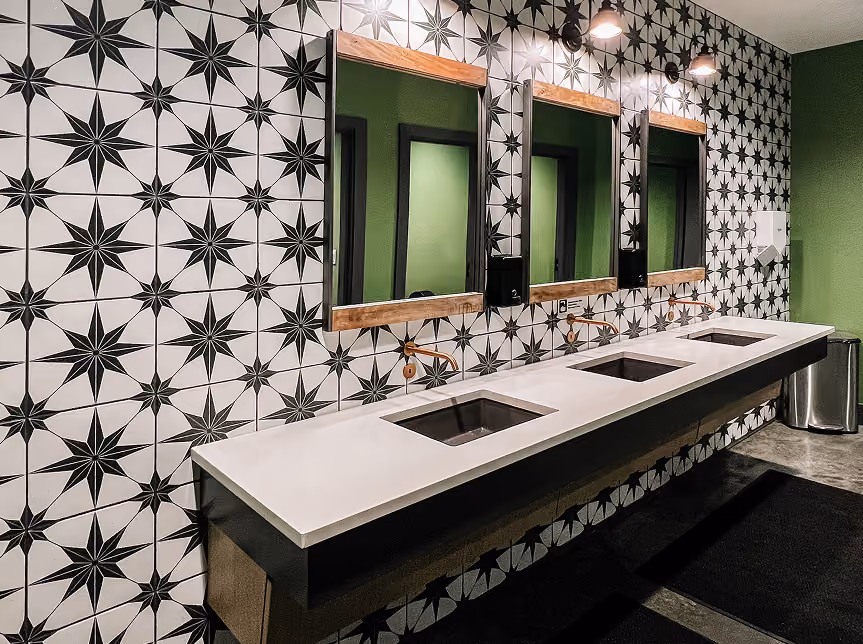 Restaurant restroom with star-patterned mosaic tile walls and dark flooring