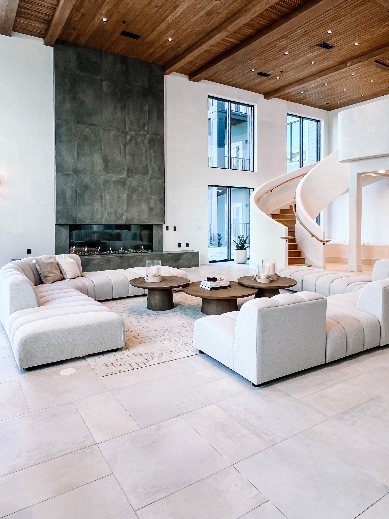 Amenity lounge with a stone fireplace, curved staircase, and tile flooring