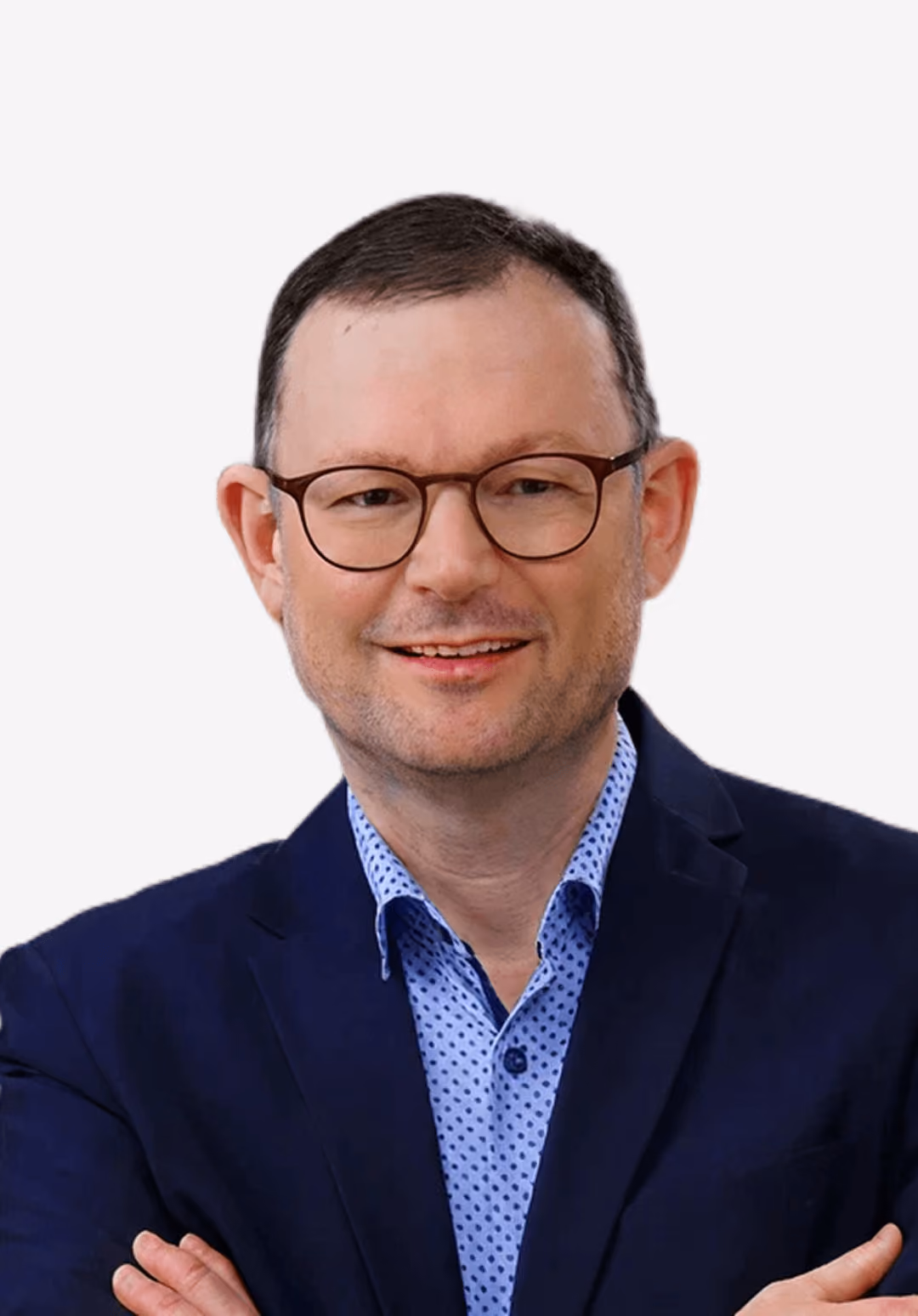 Mann mit Brille und Anzug lächelt vor weißem Hintergrund.