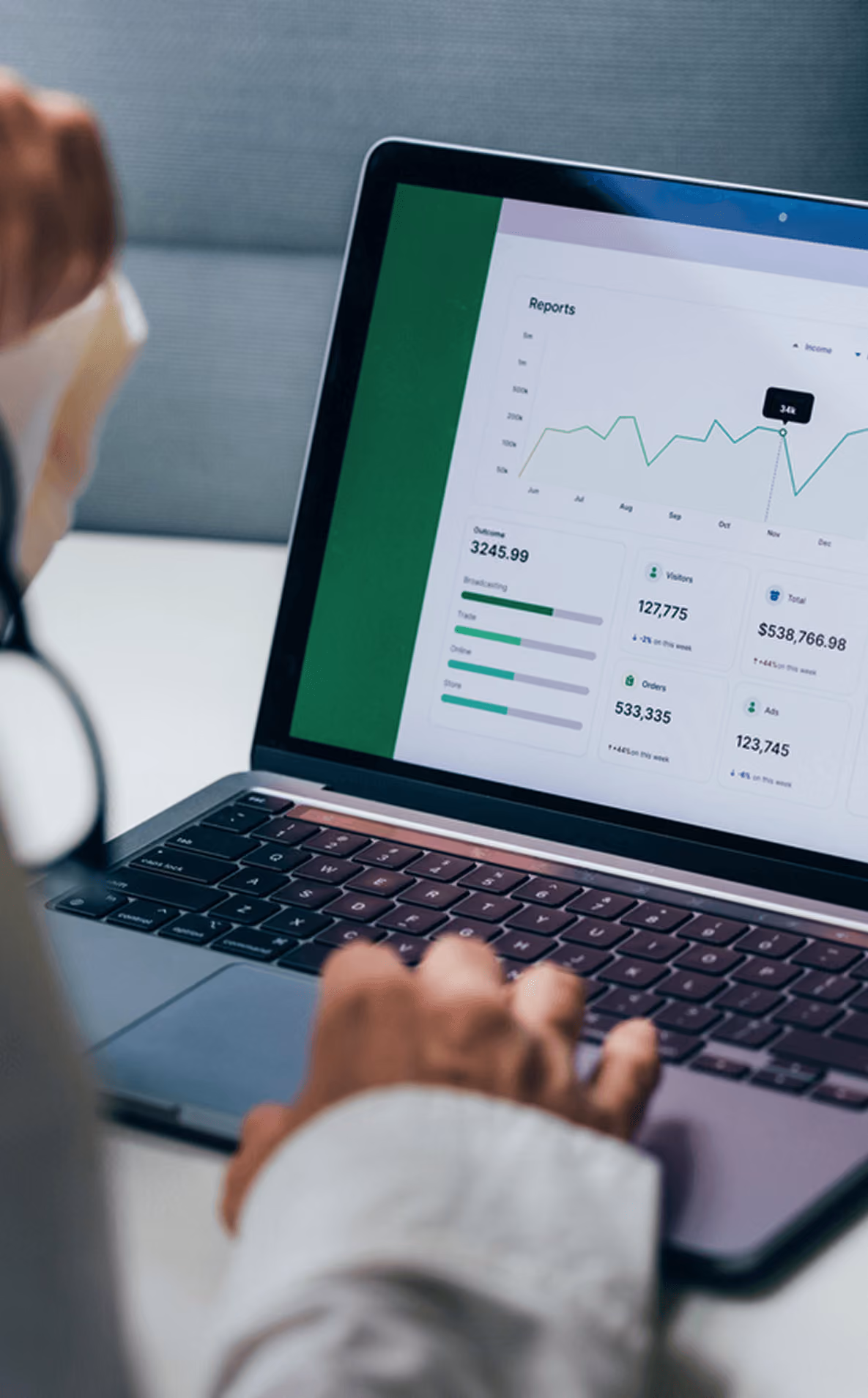 Person betrachtet Geschäftsdaten-Dashboard mit Grafiken und Statistiken auf Laptop, Zahlen in Diagrammen hervorgehoben.