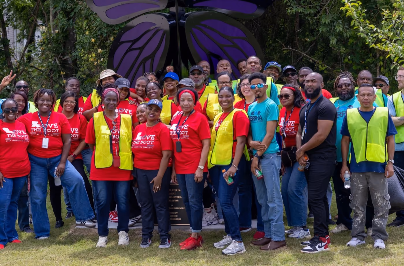 A large group of volunteers gathered outdoors in safety vests