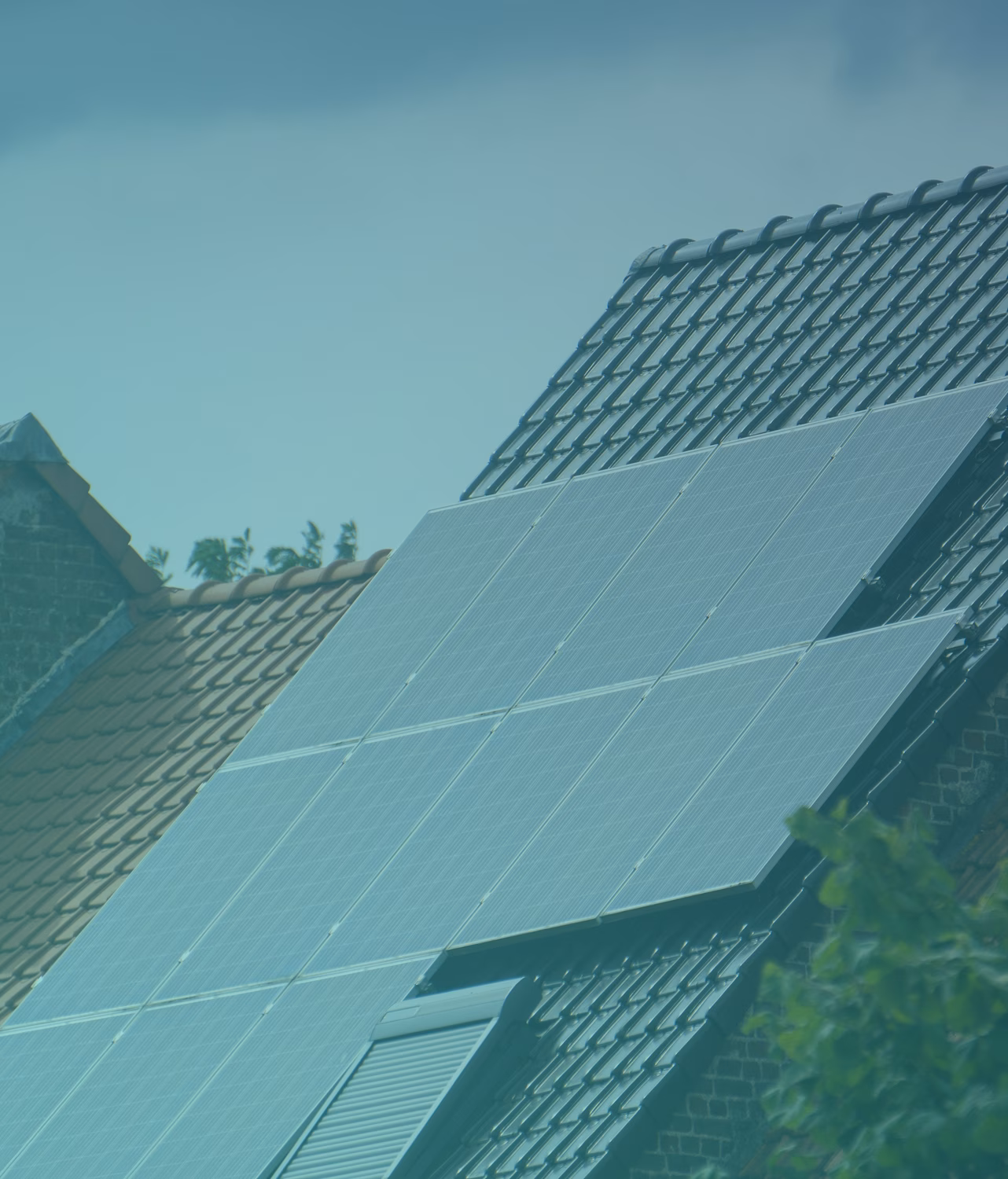 Solar panels installed on a dark tiled roof of a house under clear blue sky.
