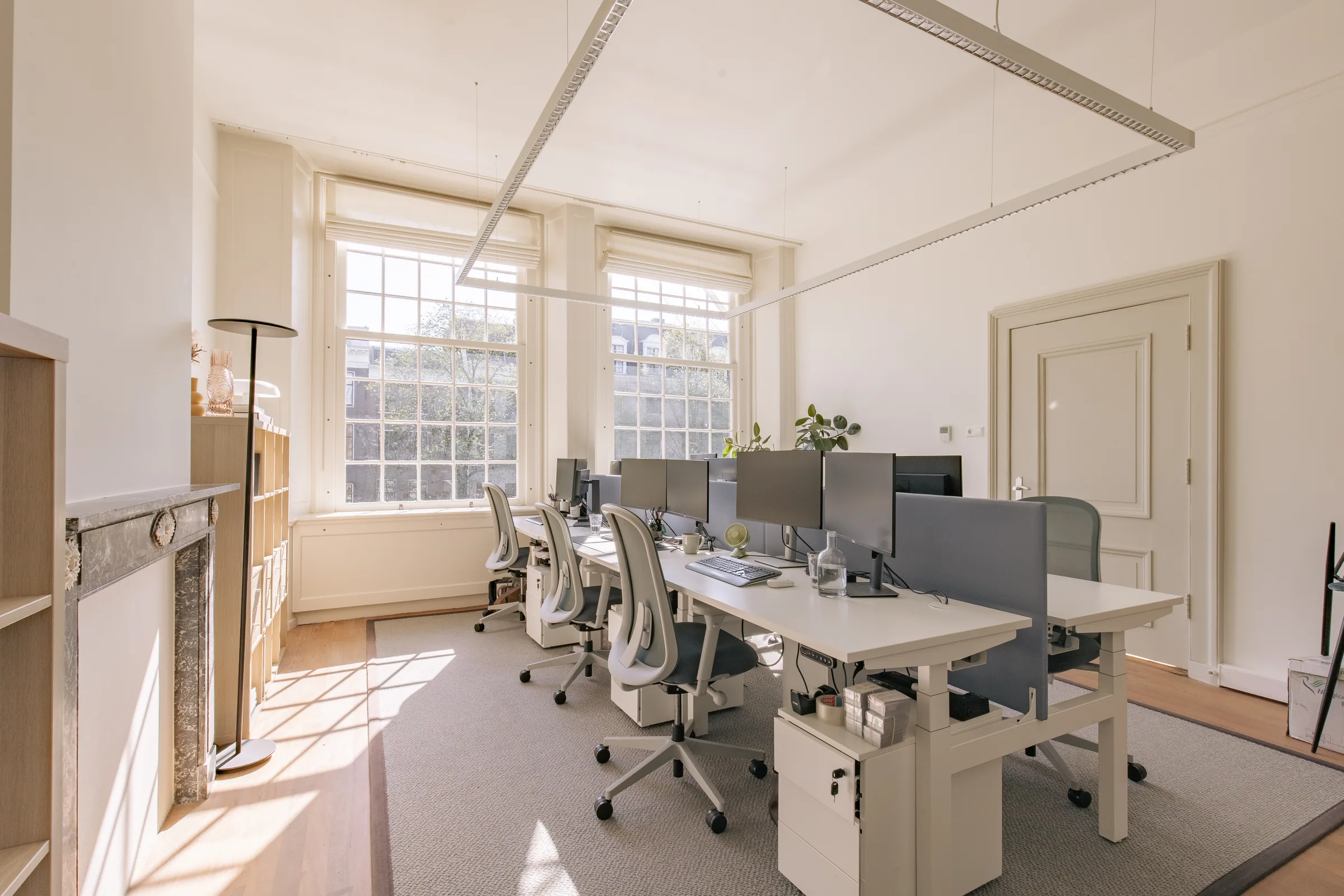 Office floor with desks, task chairs and tall windows
