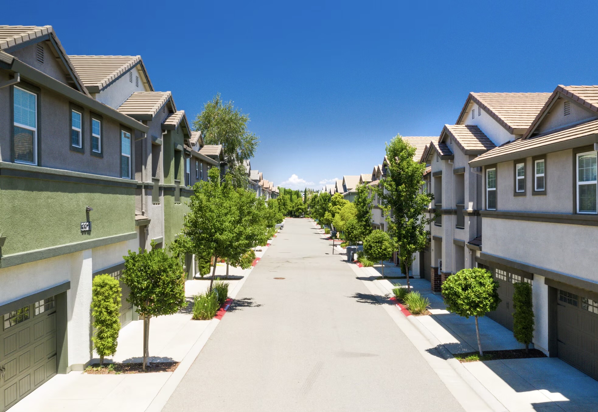 Townhomes and brick podium with sign at an entrance