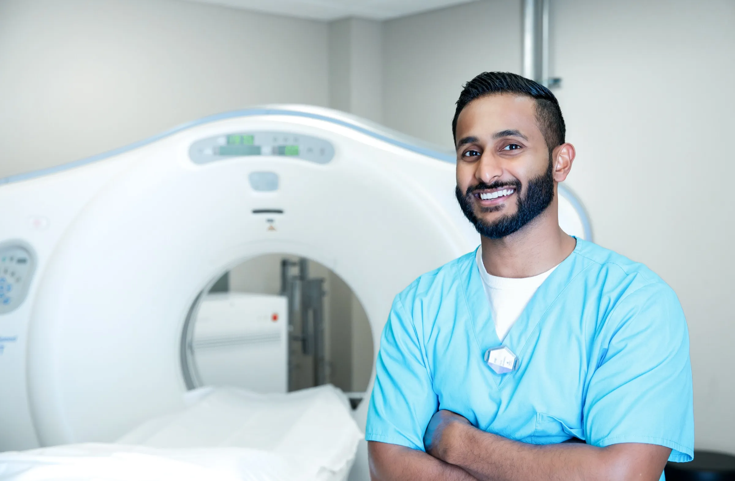 Radiologic technologist beside a CT scanner
