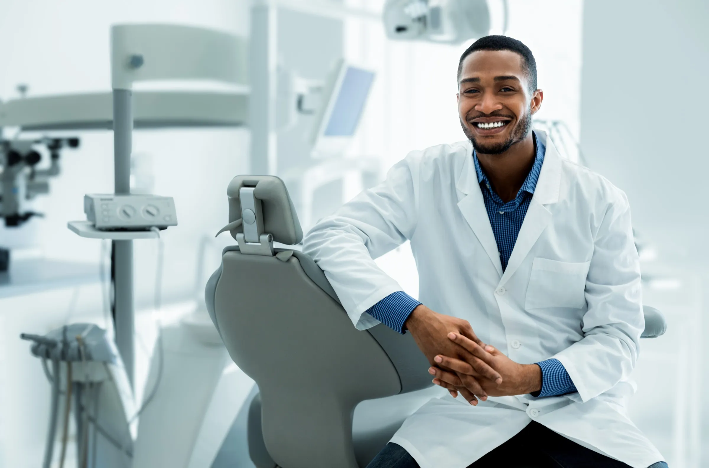 Dentist seated beside a dental chair