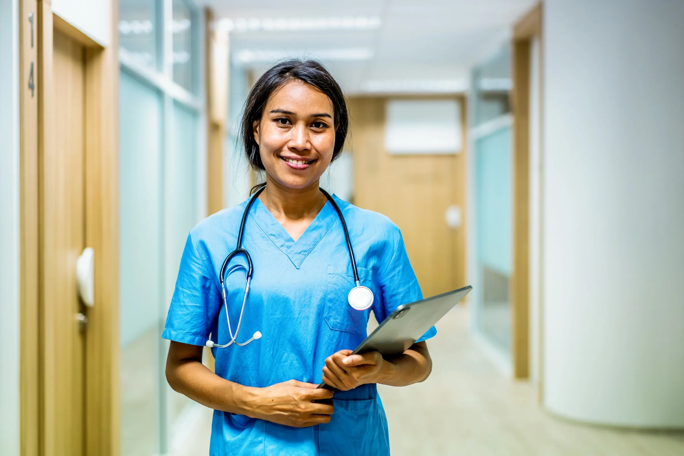 Nurse walking through a hospital corridor with a patient chart